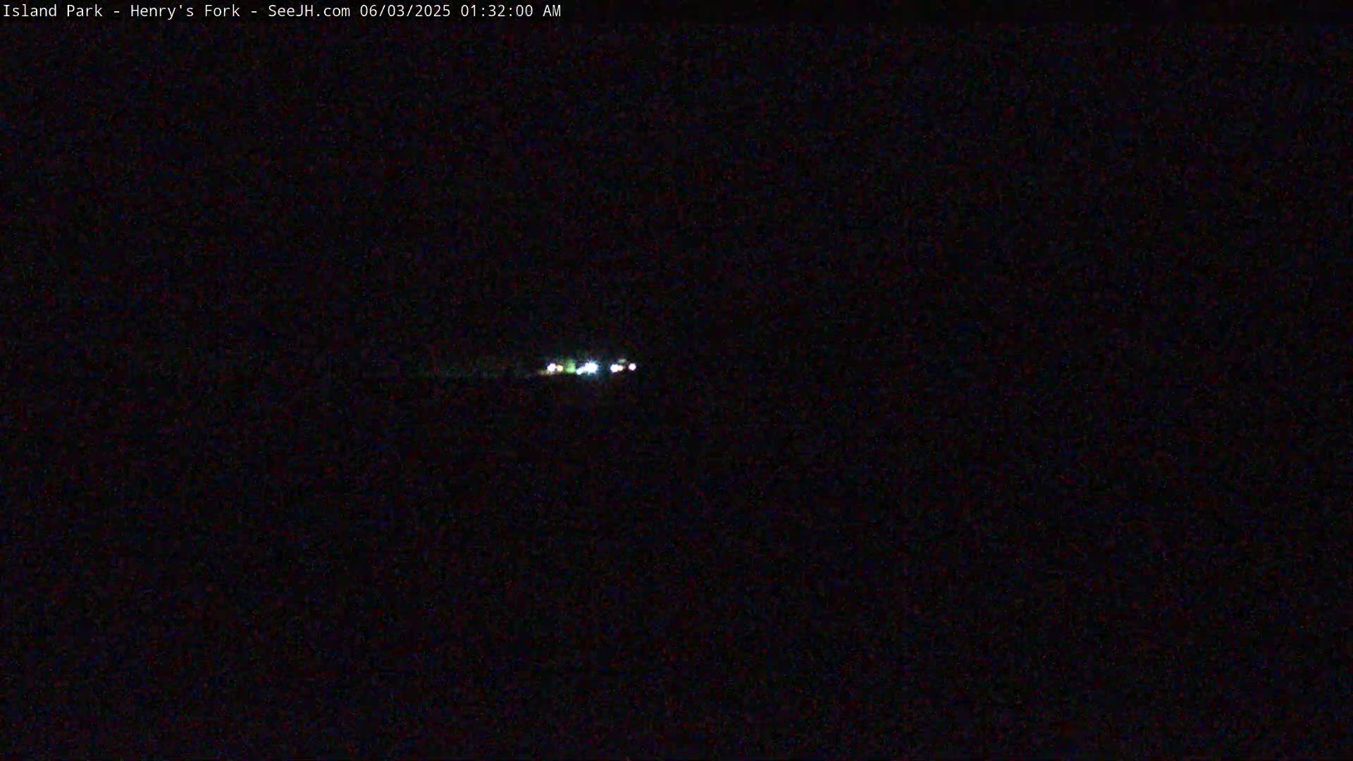 A dark, nighttime scene shows a few distant lights in the center of the frame.