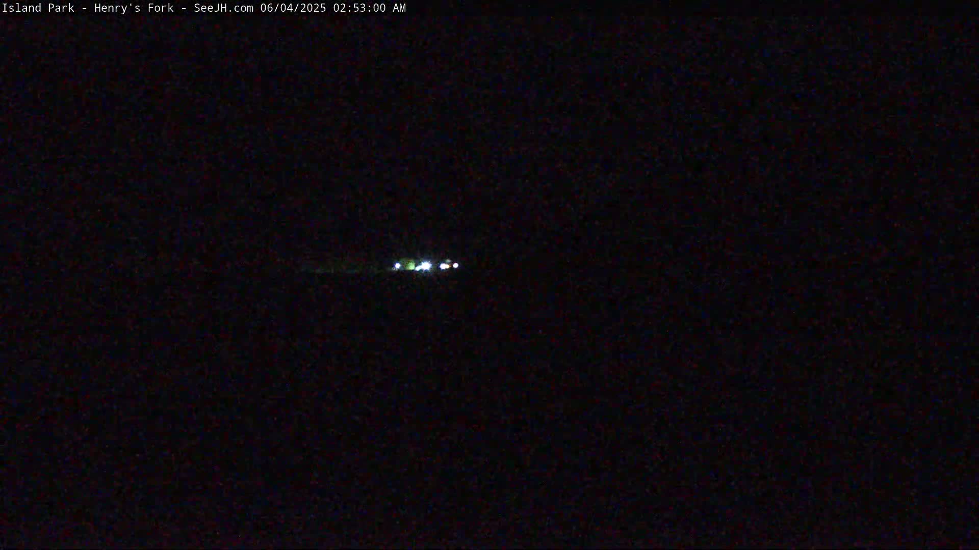 A nighttime long shot shows a few small lights in the far distance on a dark, possibly overcast night.
