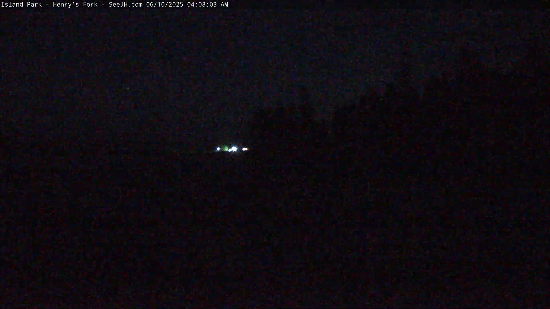 A nighttime, dark outdoor scene shows a few distant lights in the middle ground.