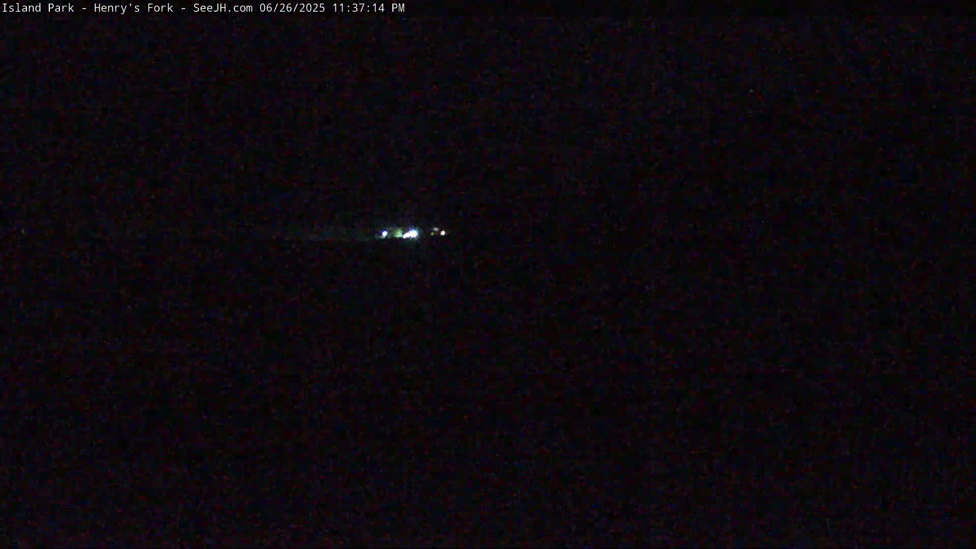 A dark, nighttime scene shows a few faint lights in the distance.