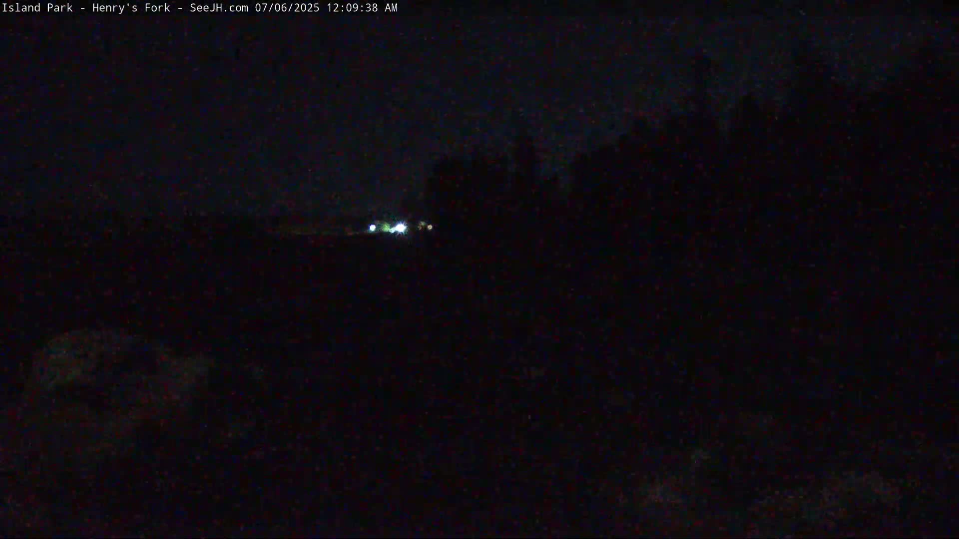 A nighttime, dark landscape is visible with a few faint lights in the distance.