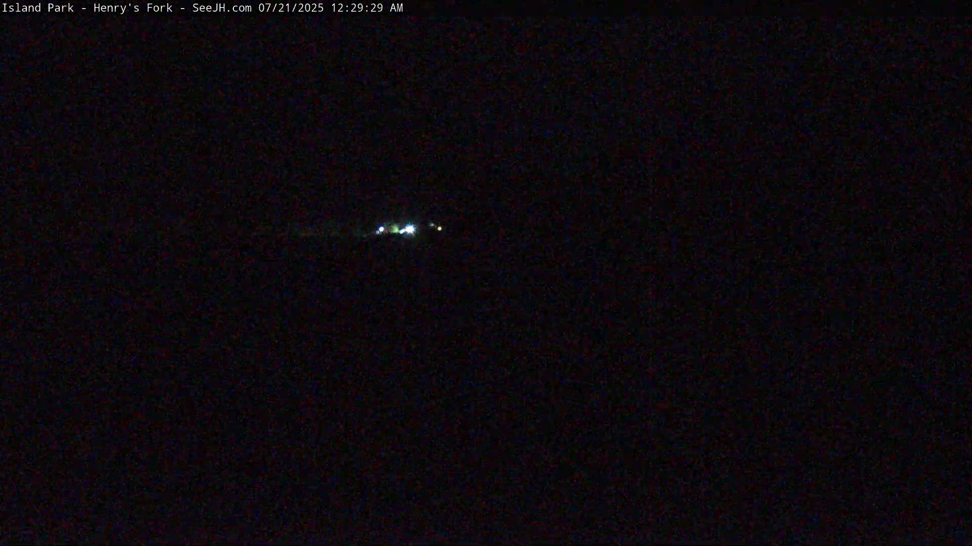A nighttime, dark scene shows a few small, distant lights.