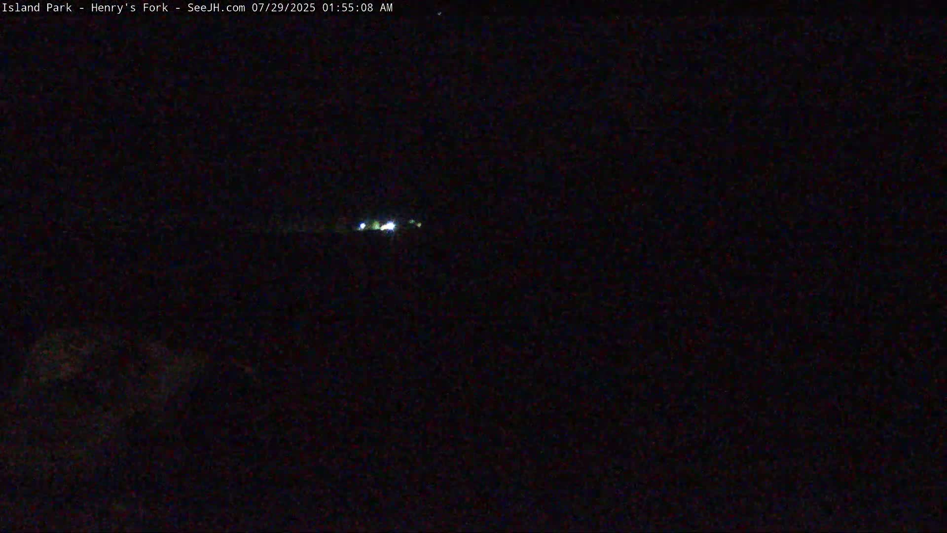 A nighttime, dark outdoor scene shows a few faint lights in the distance.