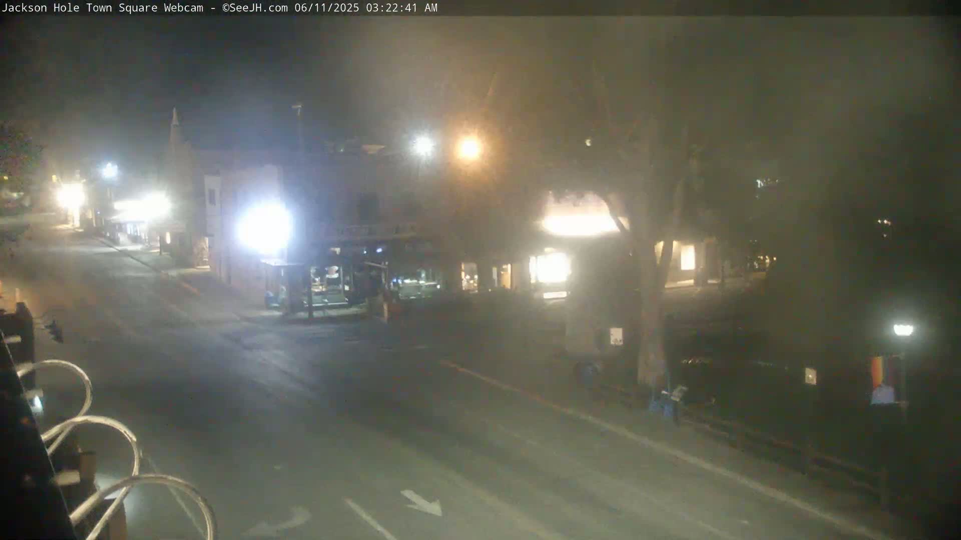 A mostly empty street at night, lined with buildings, under hazy conditions.