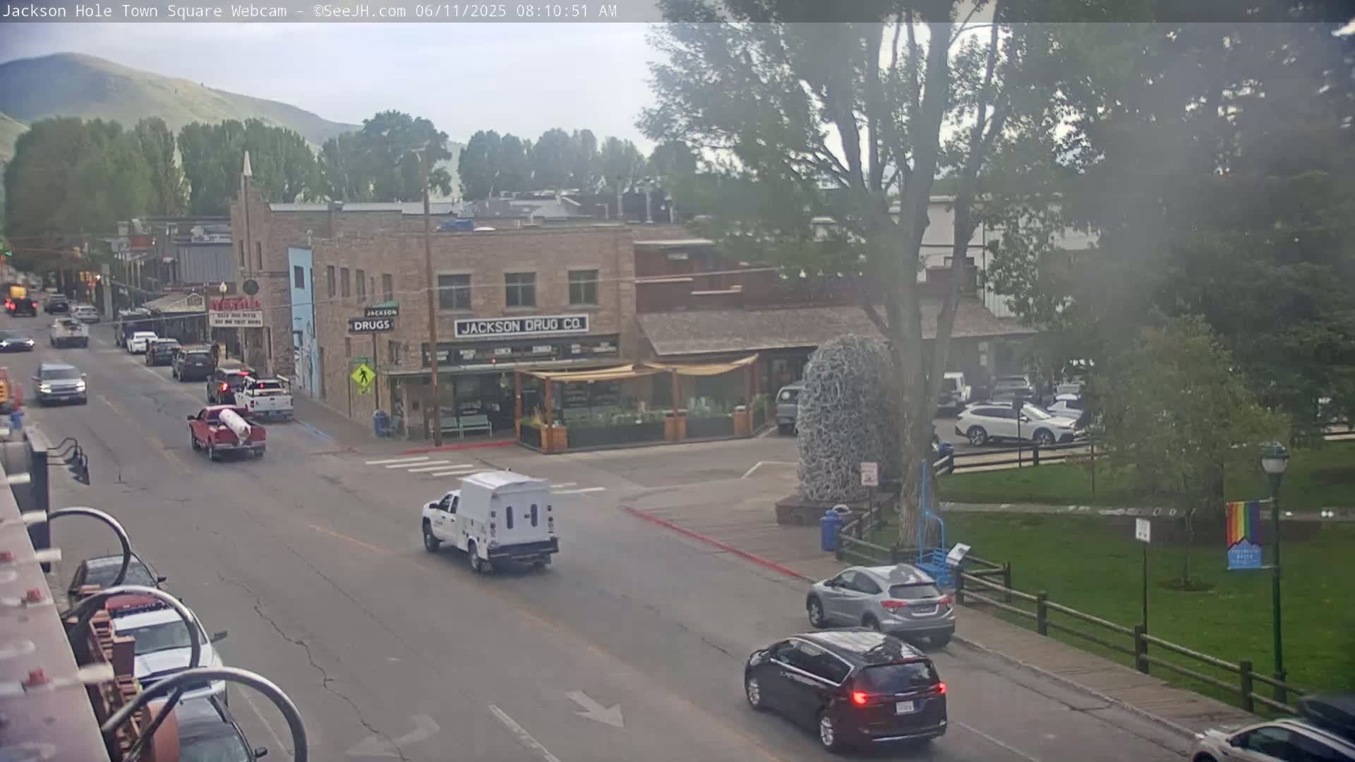 A partly cloudy day reveals a street scene in a town, with vehicles traveling on the road in front of several buildings, including one labeled "Jackson Drug Co."