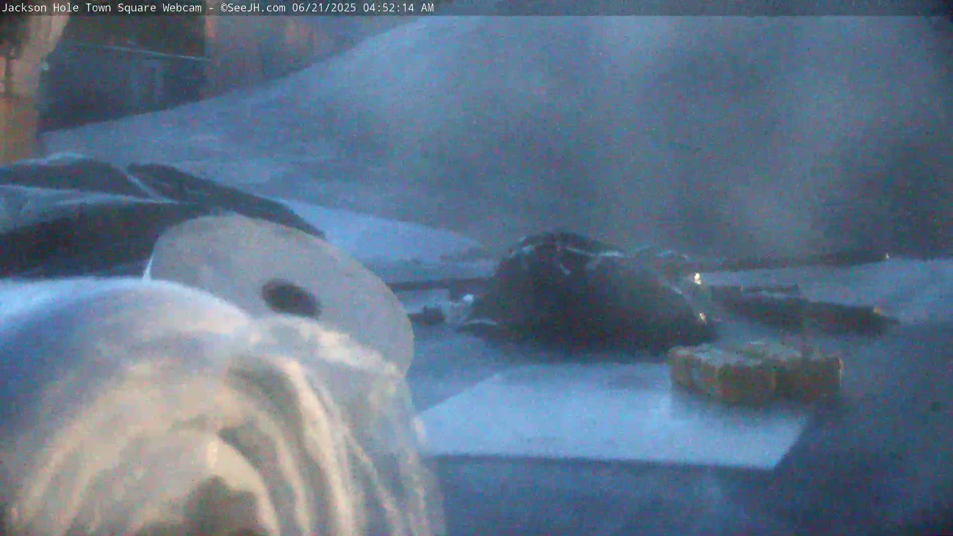 A snow-covered ground is visible with some dark objects and a light-colored object that looks like a bag in the foreground, under dim nighttime lighting.