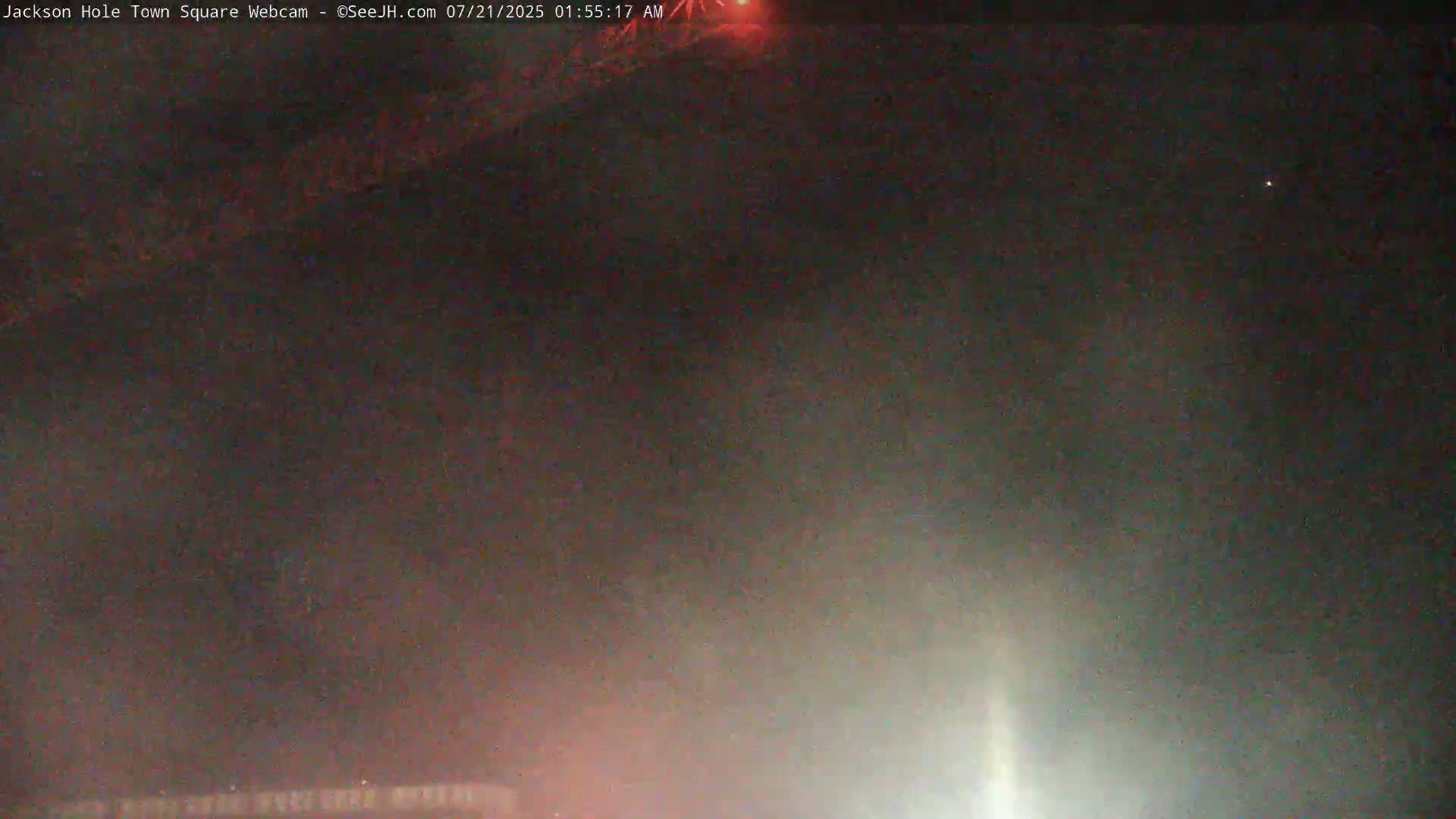 A dark, nighttime scene with a faint, light source at the bottom and a reddish glow near the top.