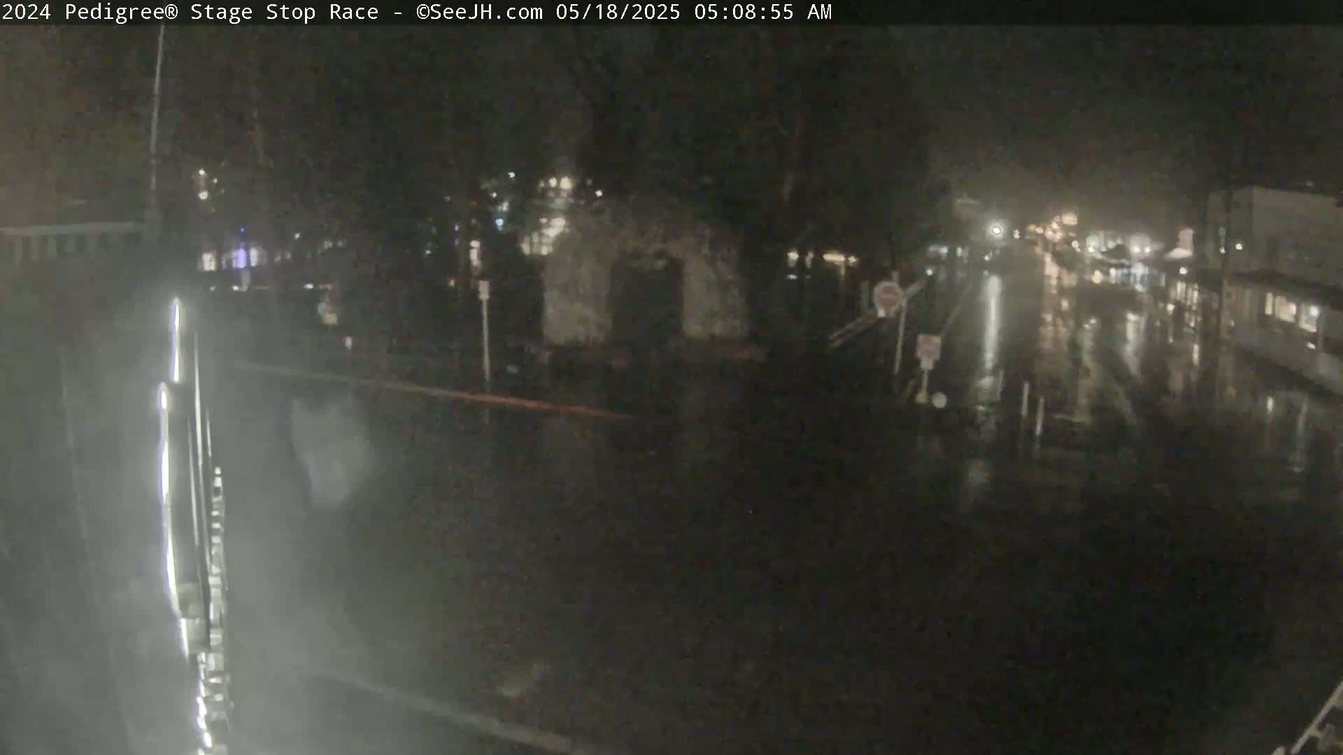 A nighttime, rain-slicked street scene shows a few indistinct figures and buildings under dim lighting.
