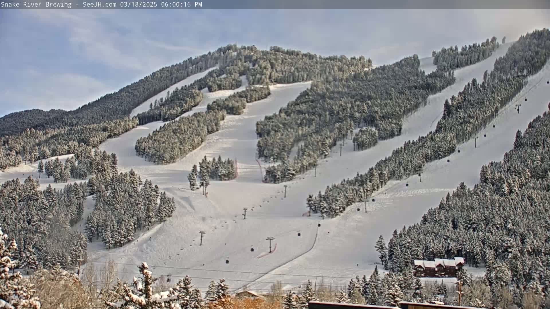A snow-covered ski resort with numerous ski runs and chairlifts is visible under a mostly clear sky.