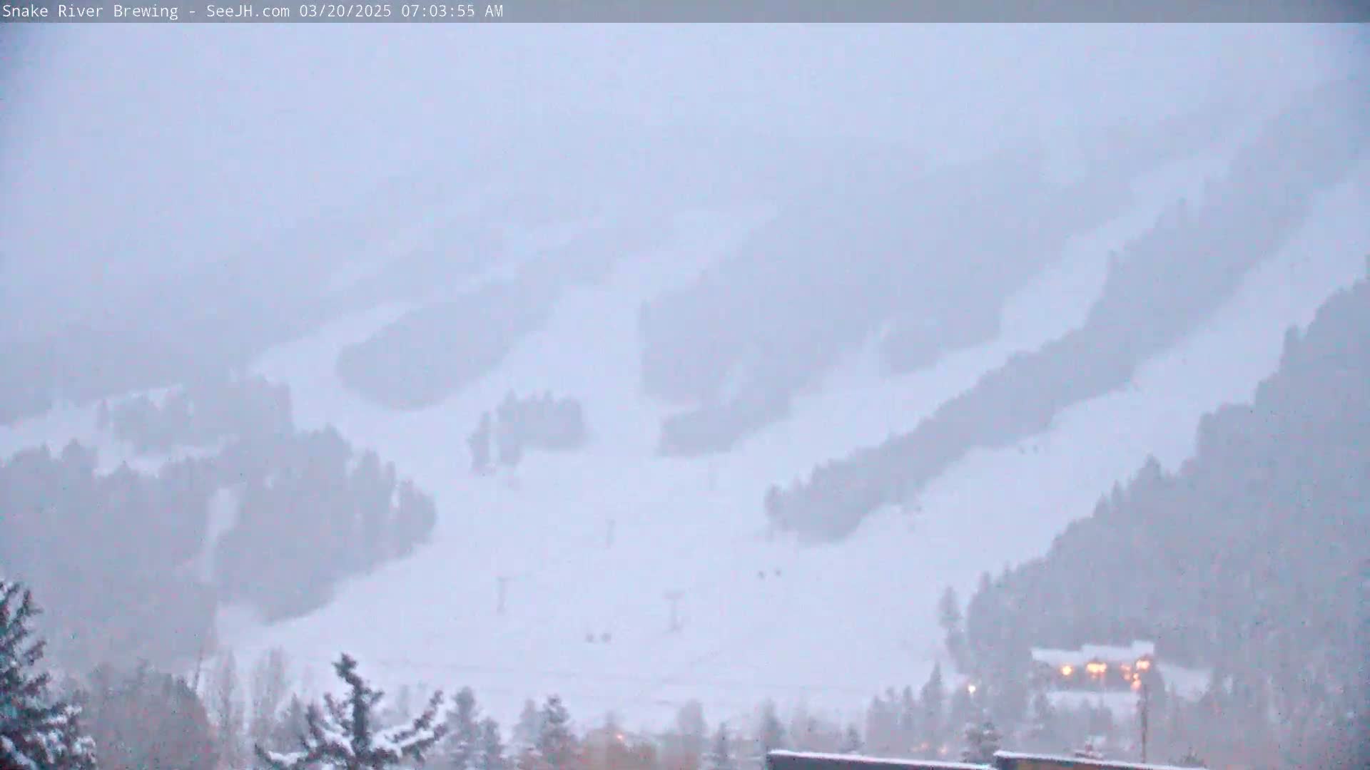 A snow-covered ski resort is visible through a heavy snowfall.