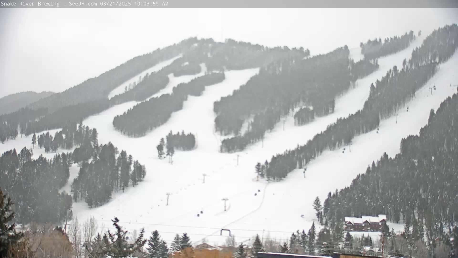 A snow-covered ski resort with several ski runs and chairlifts is visible under an overcast sky.