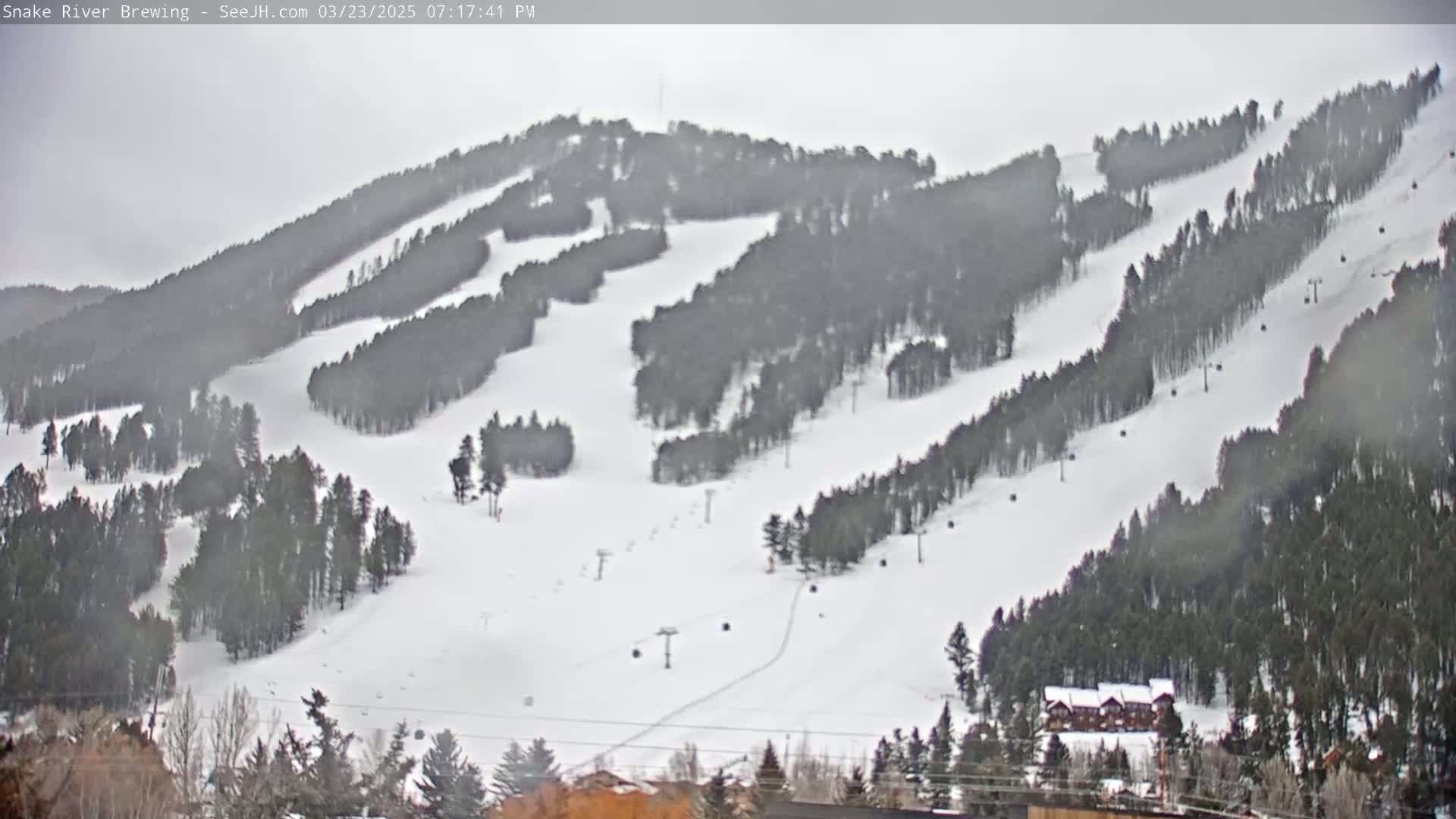 A snow-covered ski resort with several ski runs and chairlifts is visible under an overcast sky.