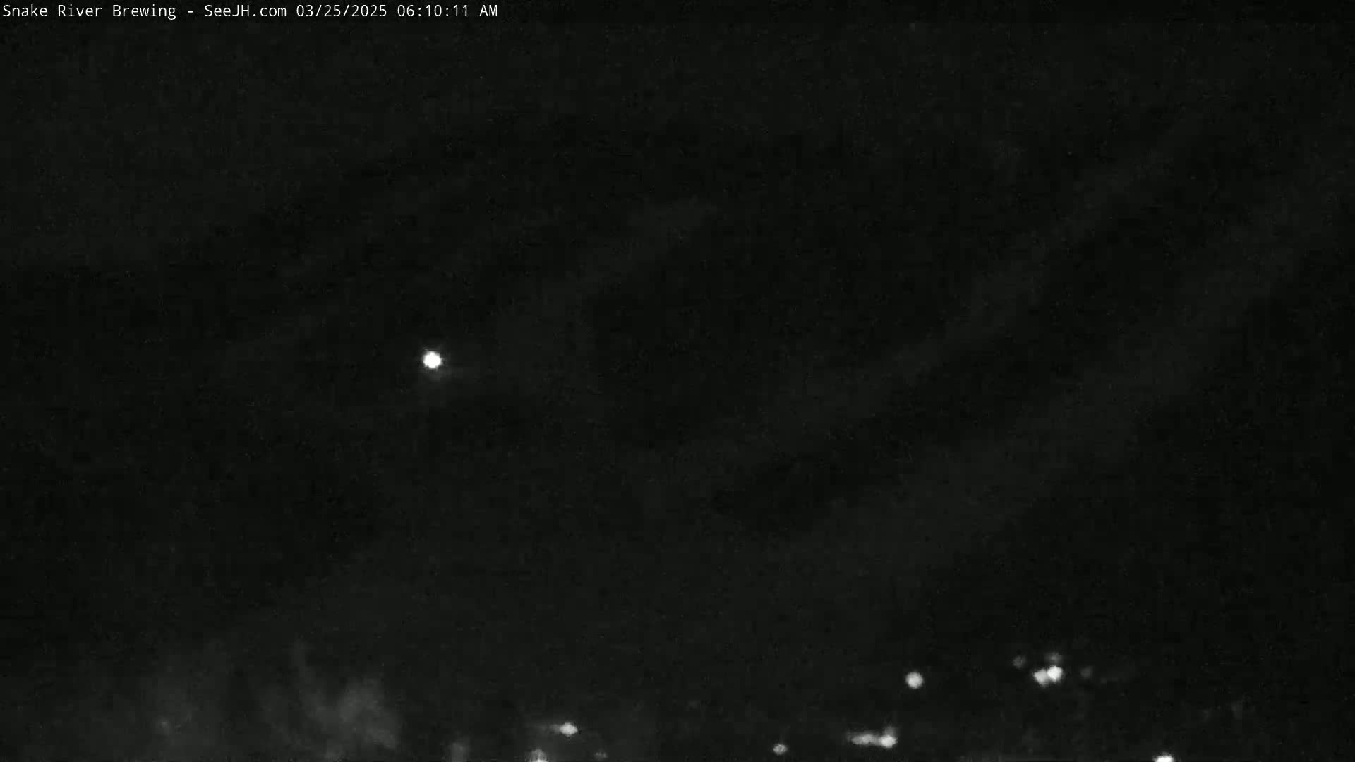 A bright light, possibly the moon, is visible in a dark night sky with faint clouds and distant lights below the horizon.