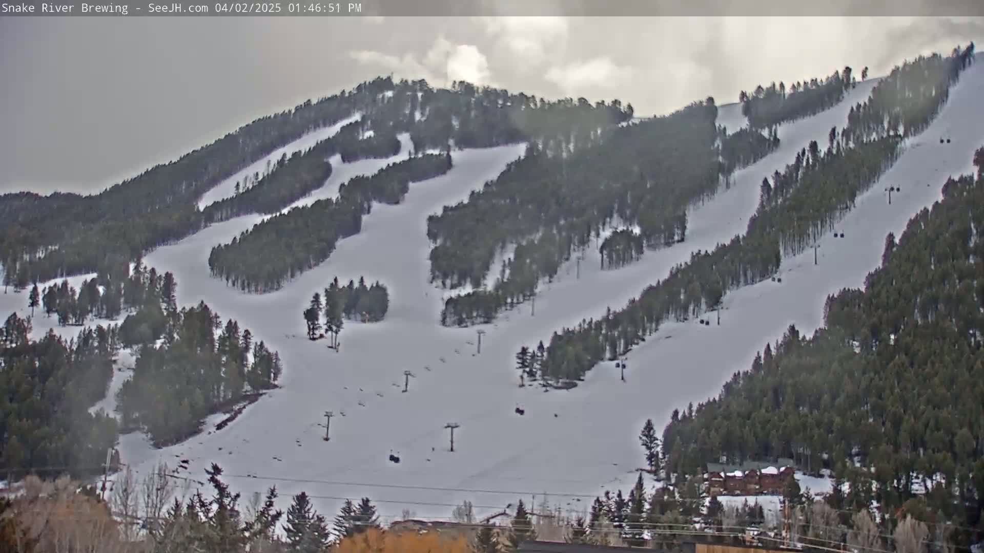 A snow-covered ski slope with several ski lifts is visible under an overcast sky.