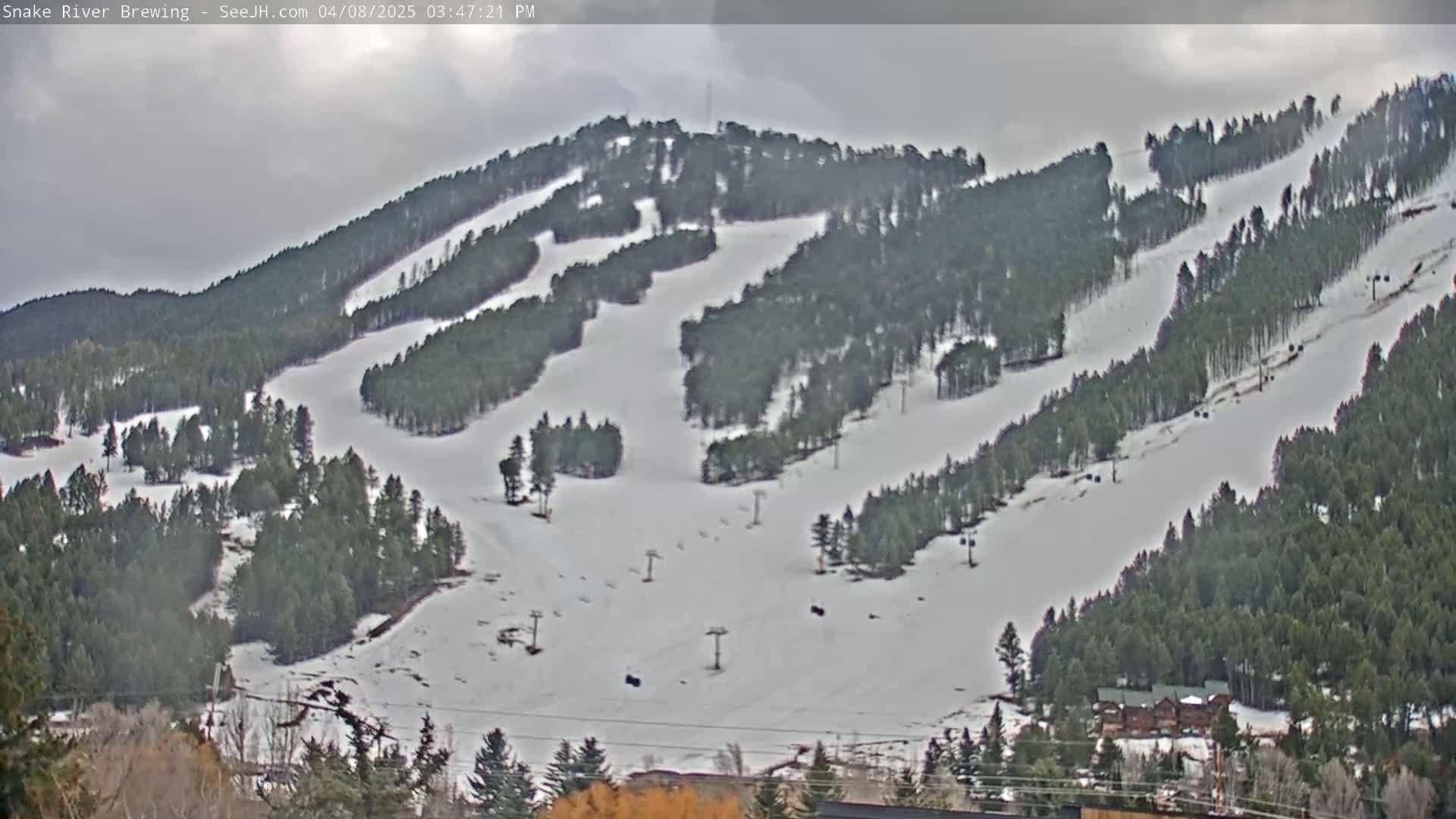 A snow-covered ski resort with several ski runs and chairlifts is visible under an overcast sky.