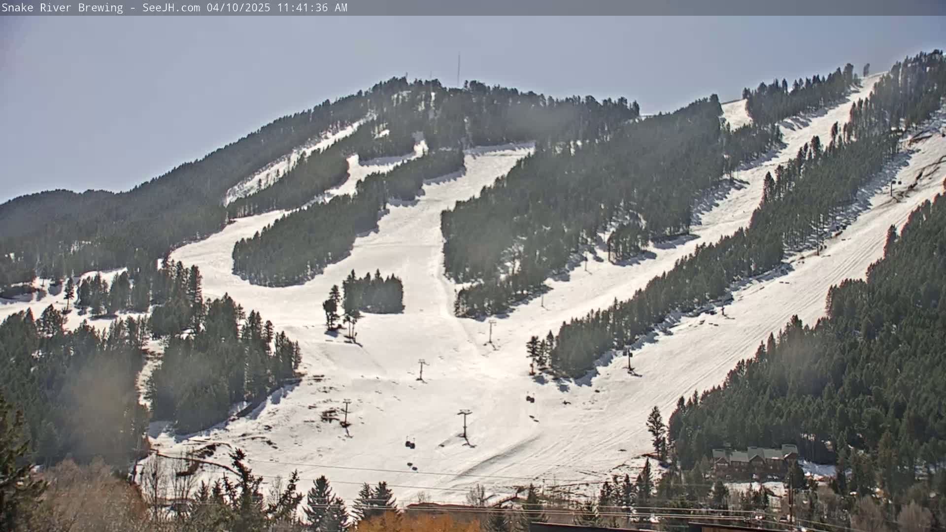 A snow-covered ski resort with numerous runs and ski lifts is visible on a sunny day.