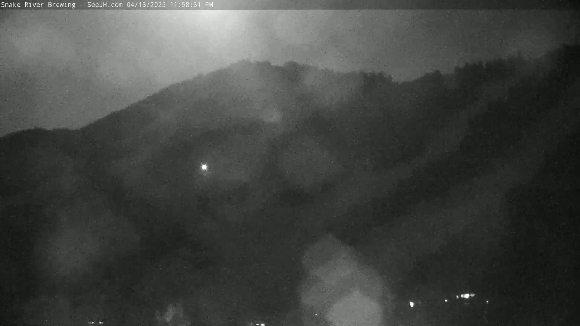 A nighttime, low-light image shows a dark, hazy hill shrouded in a misty or cloudy atmosphere.