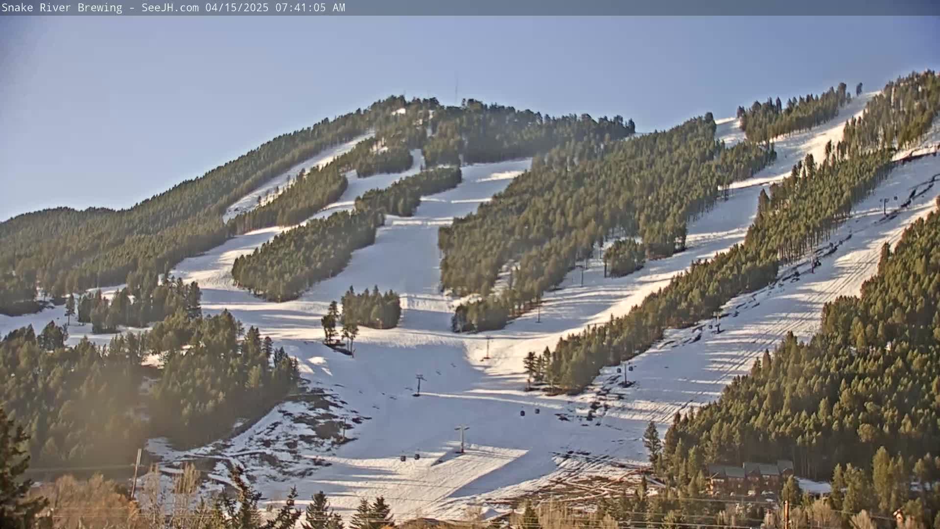 A snow-covered ski resort with numerous runs and ski lifts is visible under a clear, bright sky.