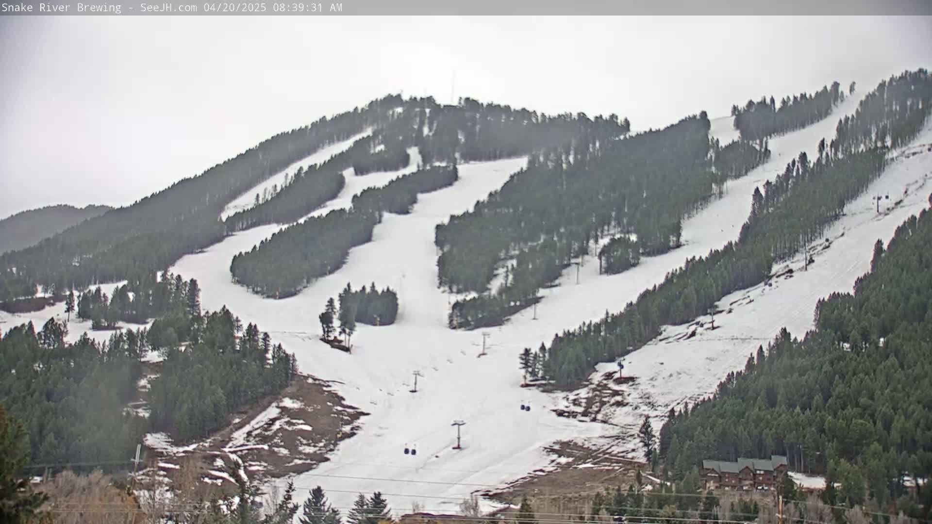 A snow-covered ski resort with several ski runs and chairlifts is visible under an overcast sky.