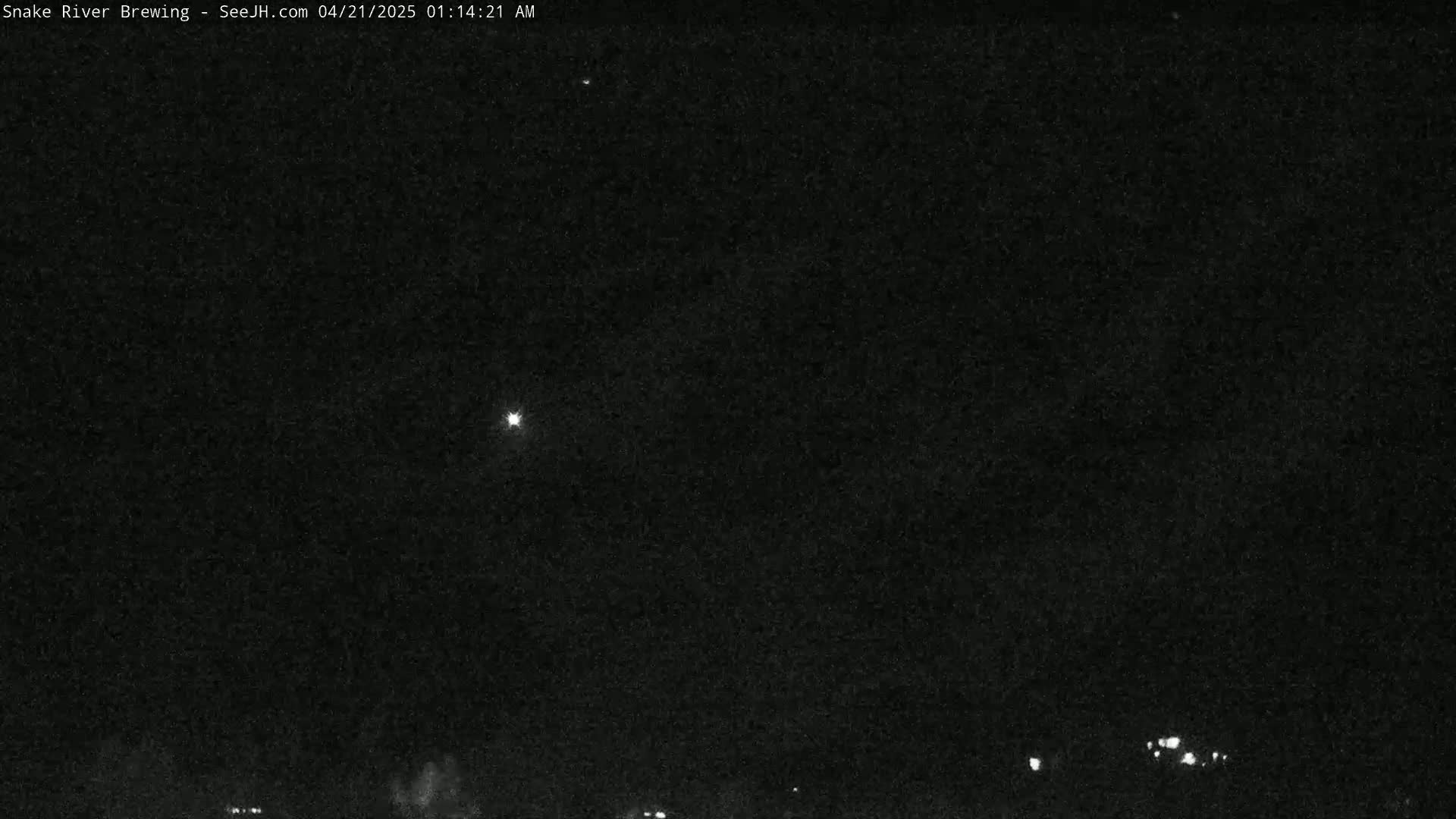 A nighttime, low-light outdoor image shows a dark sky with a few faint lights visible near the horizon and several brighter lights higher in the sky.