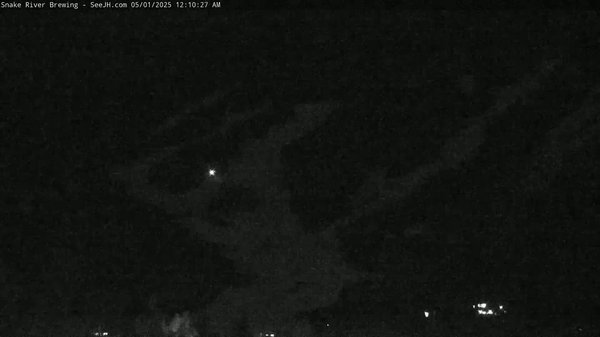 A nighttime, dark sky shows a bright light and faint clouds.