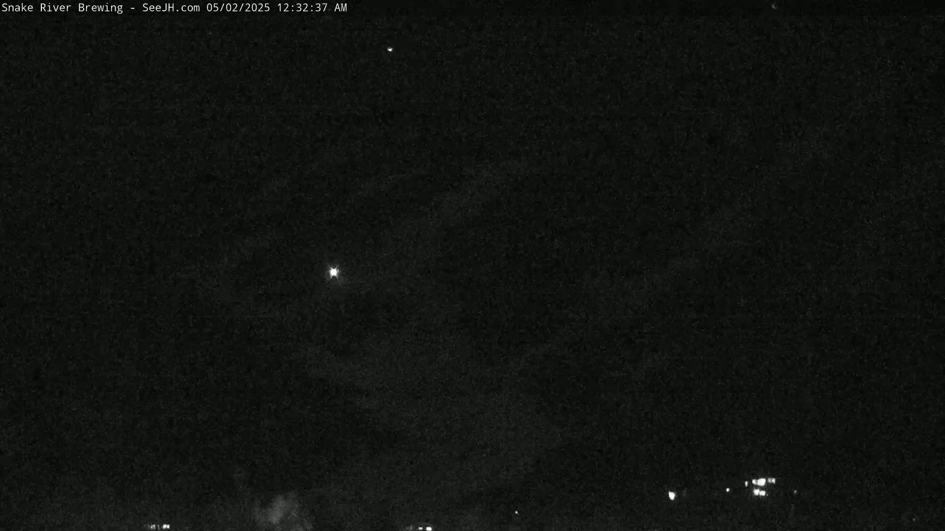 A nighttime, dark sky shows a few distant lights on the horizon and several bright lights in the sky.