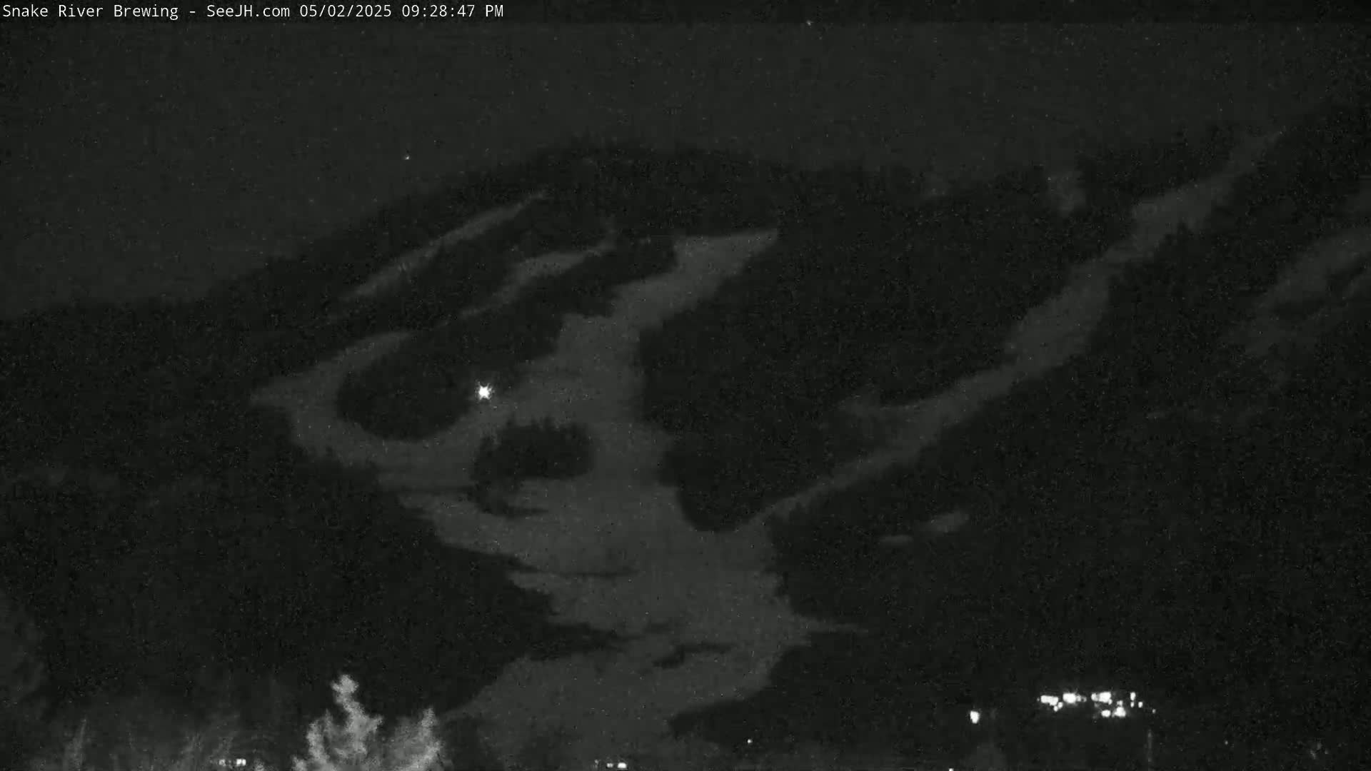 A nighttime, low-light view of a snow-covered mountainside under a dark sky.