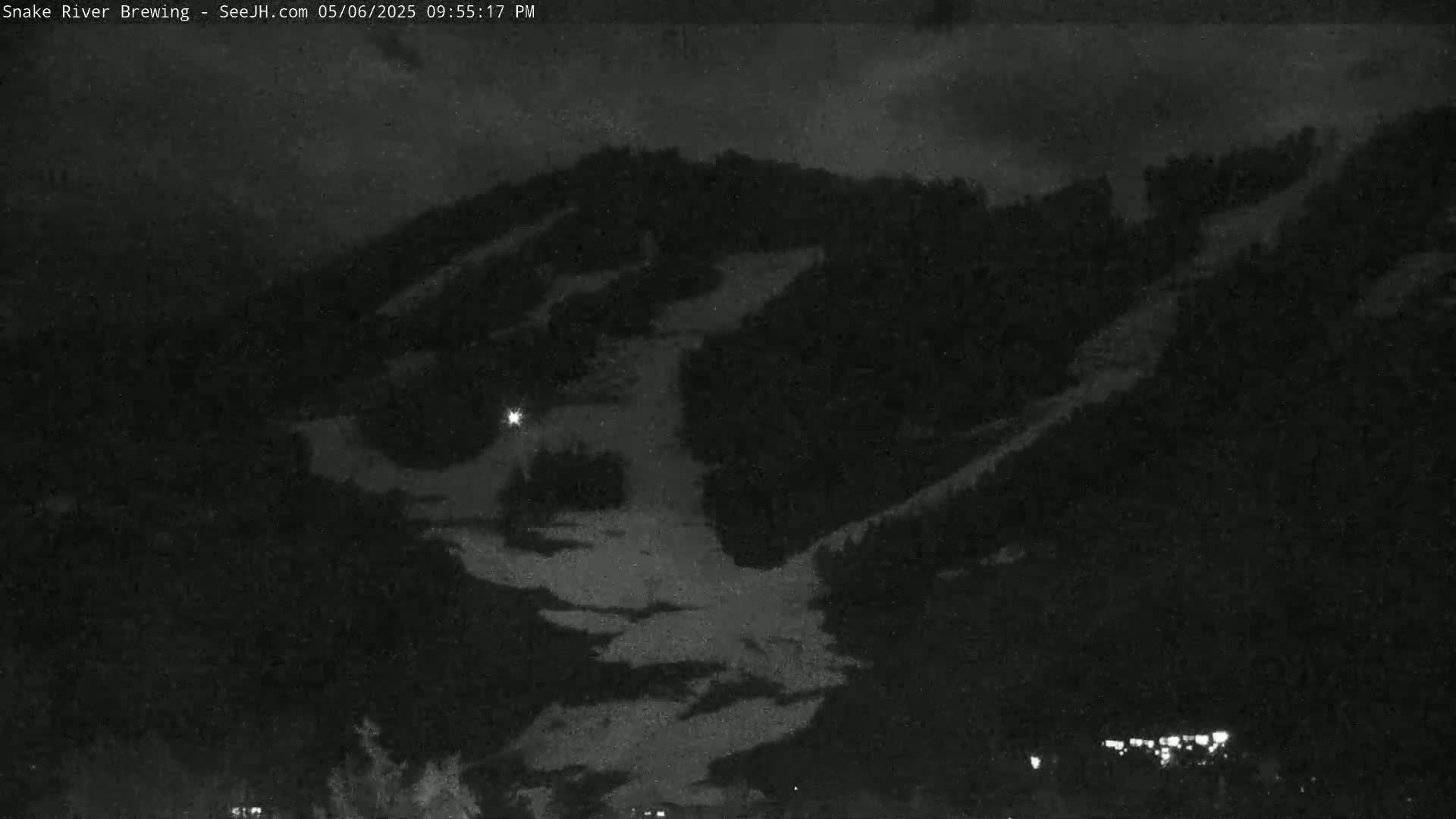 A nighttime long shot shows a dark mountainside with patches of snow under a cloudy sky.