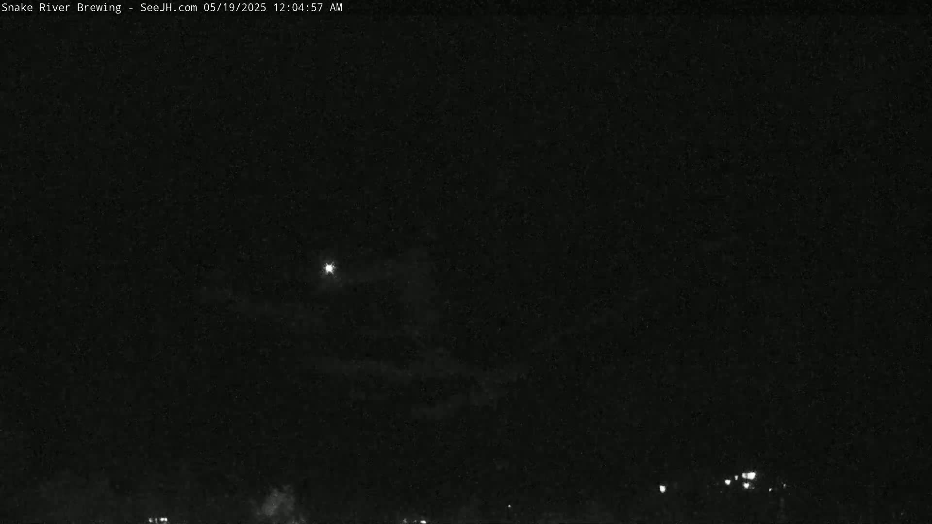 A nighttime, dark sky shows a bright light and faint clouds, with a few distant lights visible at the bottom.
