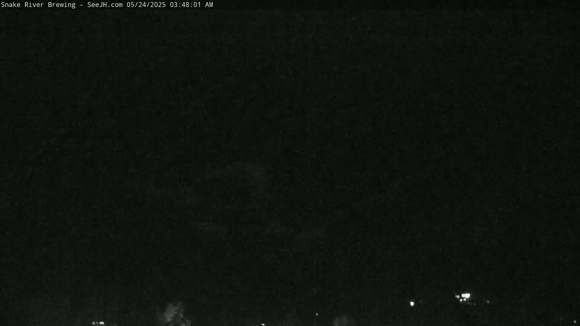 A nighttime, dark outdoor scene shows a few distant lights on the horizon under a mostly clear sky.