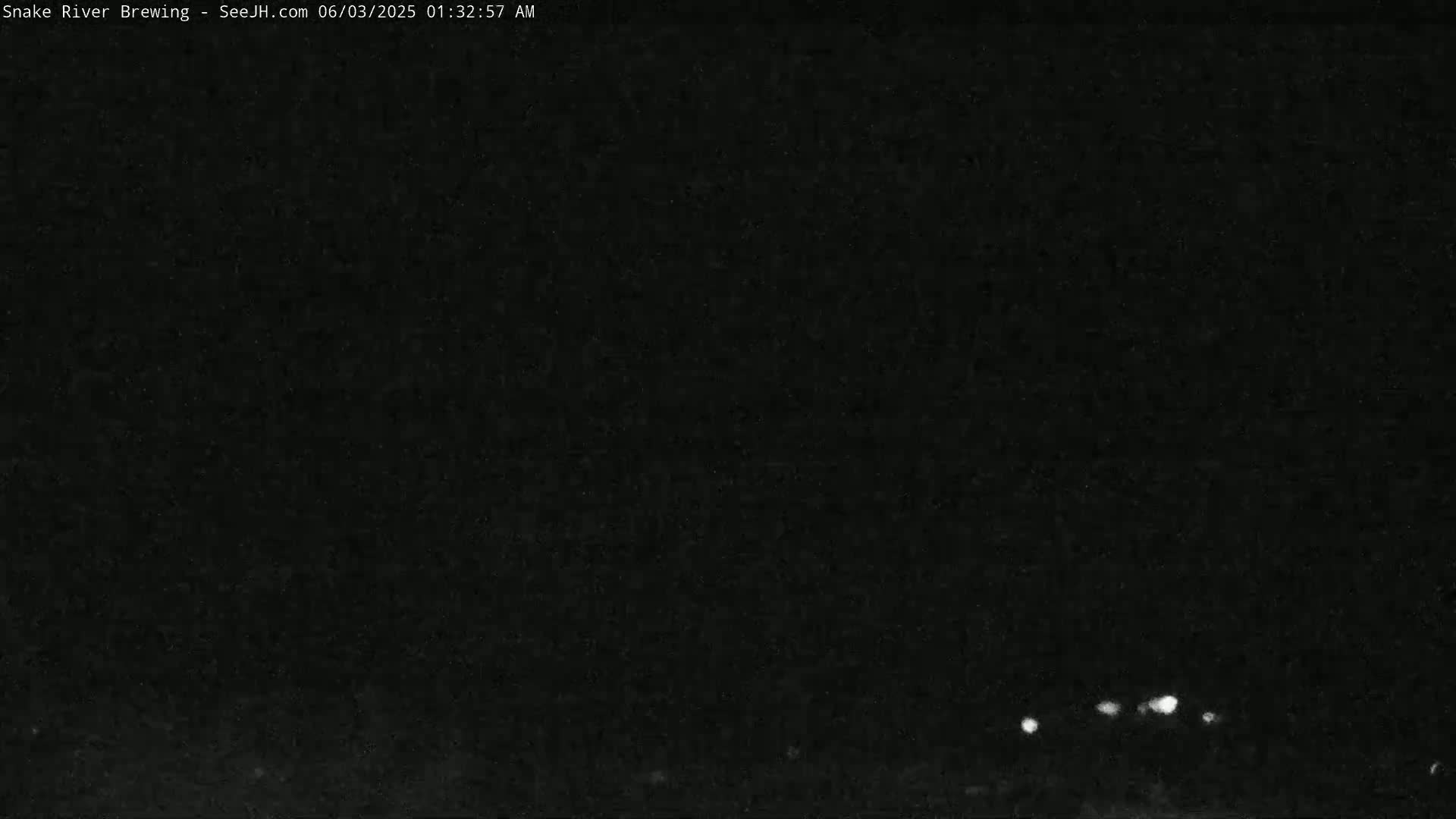 A nighttime, dark image shows a few small, bright lights in the distance.