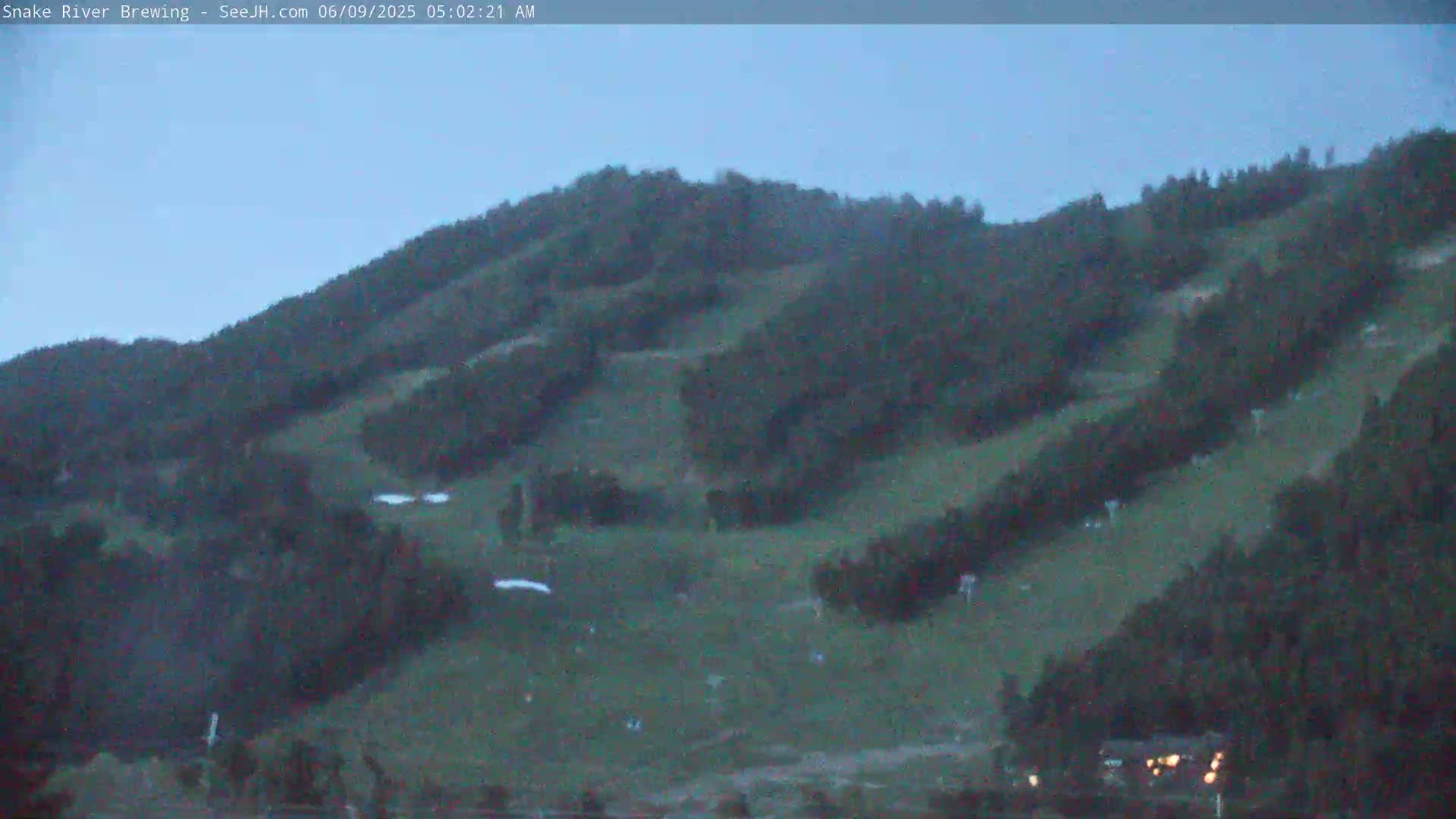 A dark-green, tree-covered hillside is visible under a twilight sky.