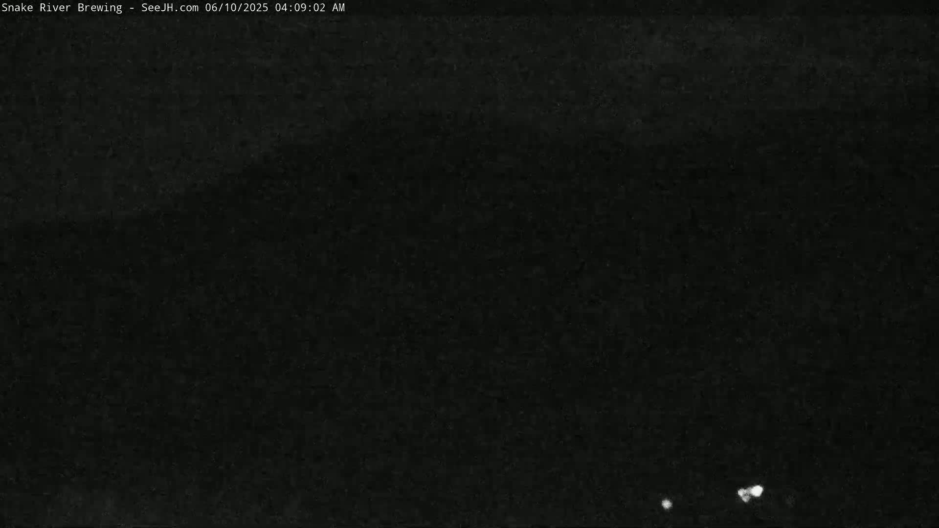 A nighttime, low-light image shows a dark, mostly featureless scene with a few small, bright spots near the bottom.