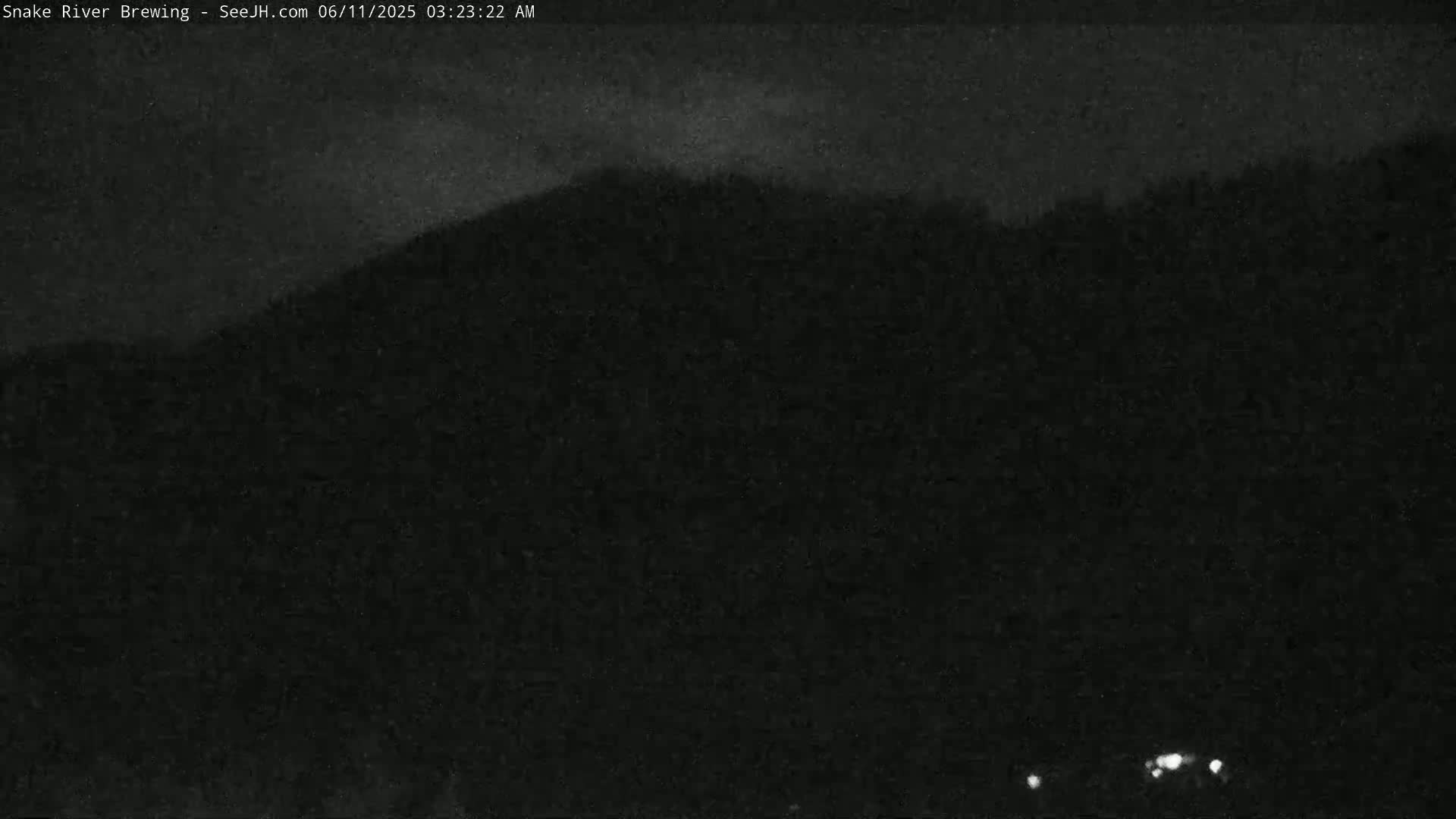 A dark, nighttime scene shows a silhouetted hill under a cloudy sky.