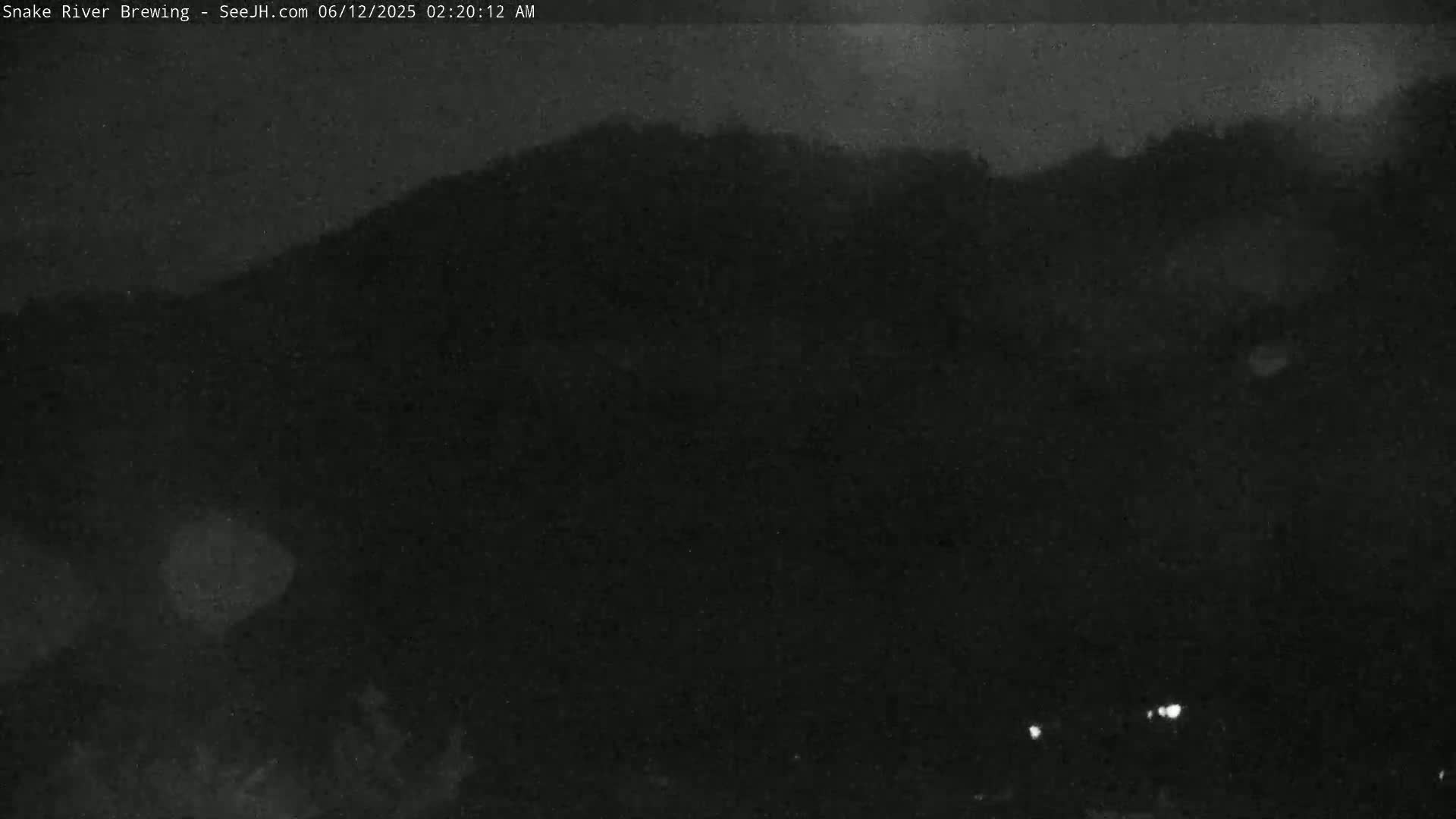 A dark, nighttime scene shows a hill silhouetted against a cloudy sky.