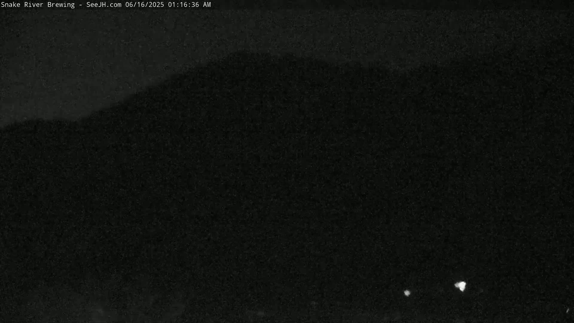 A dark, nighttime image shows a hill or mountain silhouetted against a very dark sky.