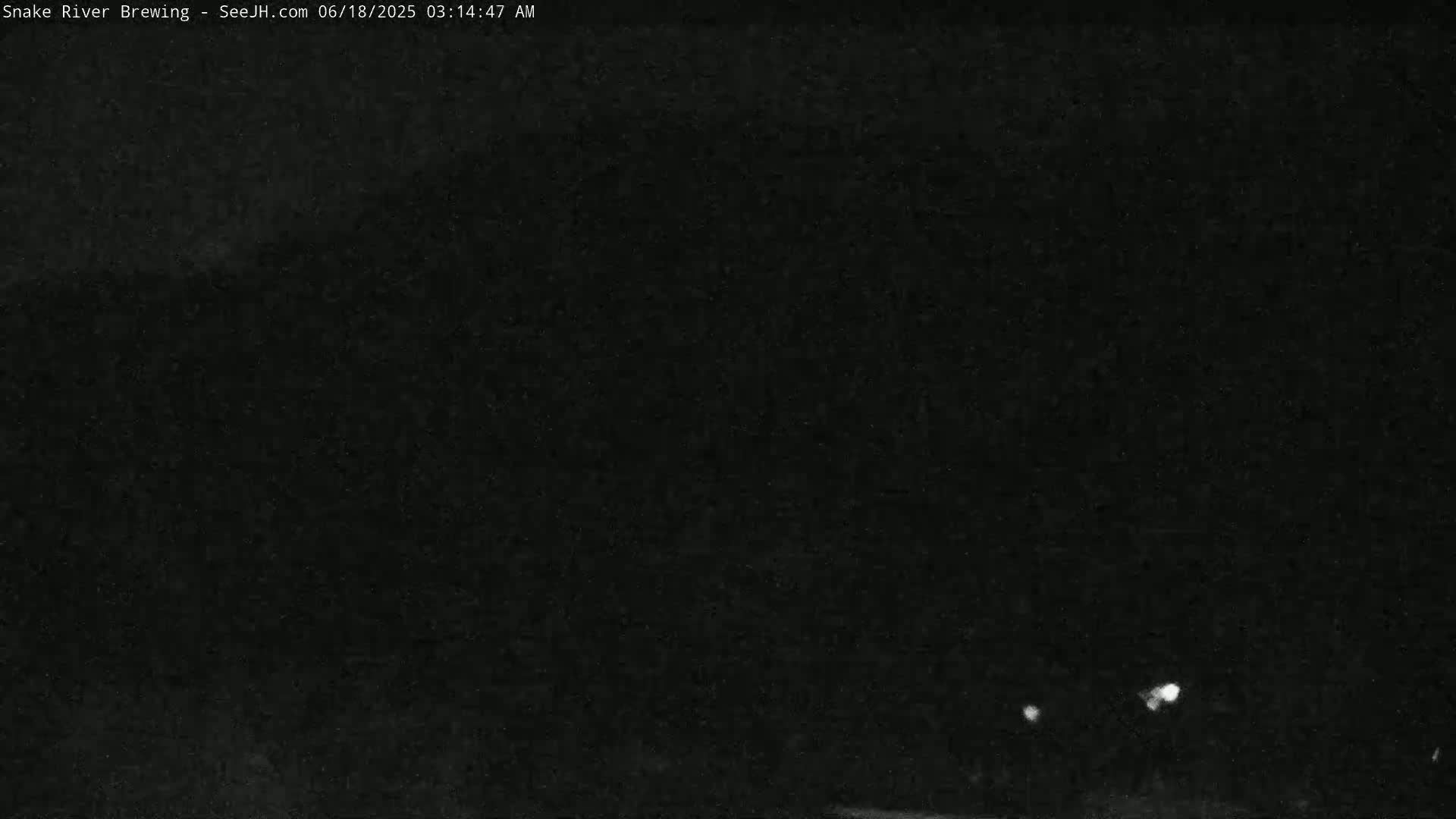 A dark, nighttime image shows a few small, bright lights in the distance.