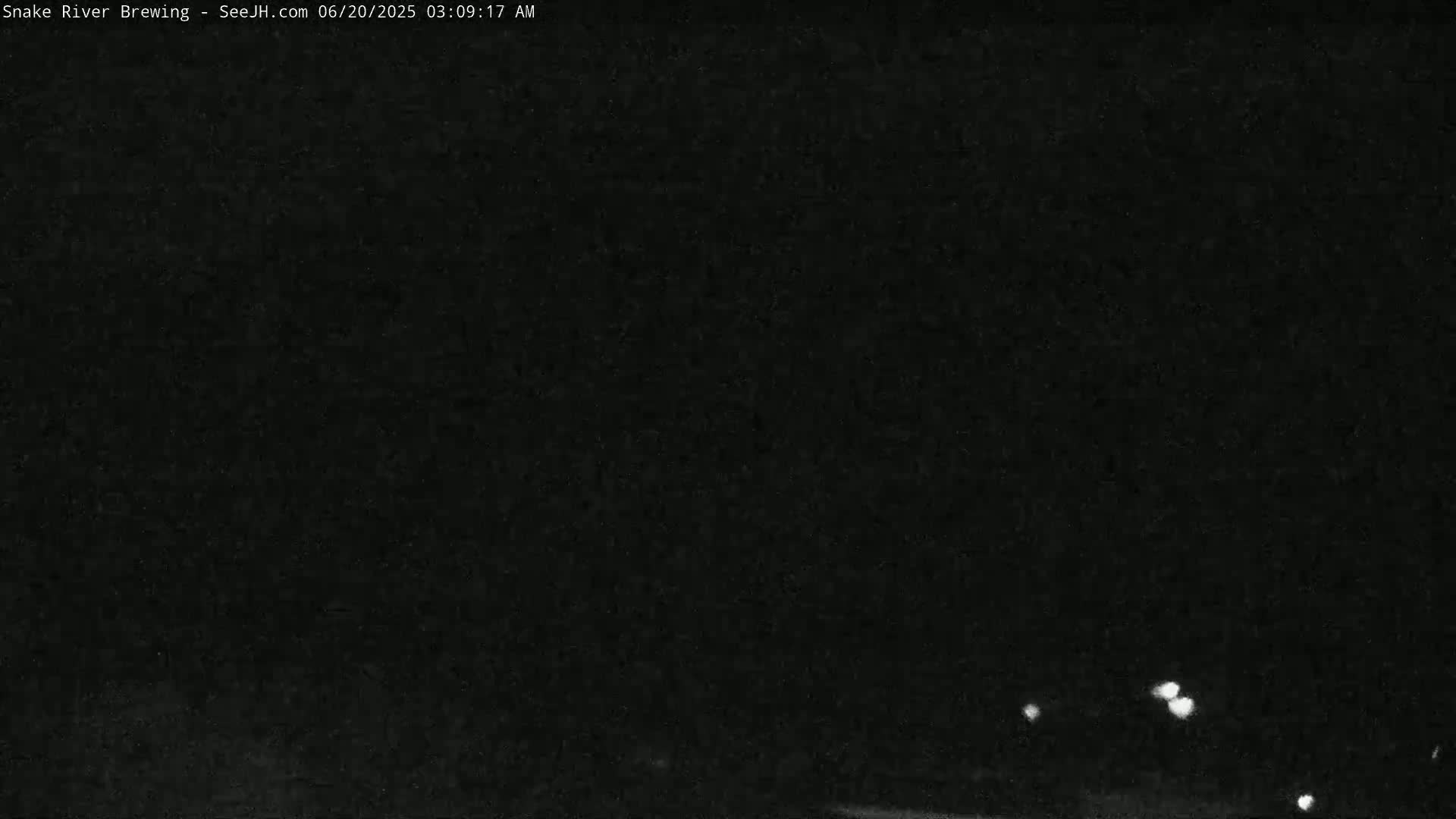 A dark, nighttime scene shows a few distant lights in the lower portion of the frame.