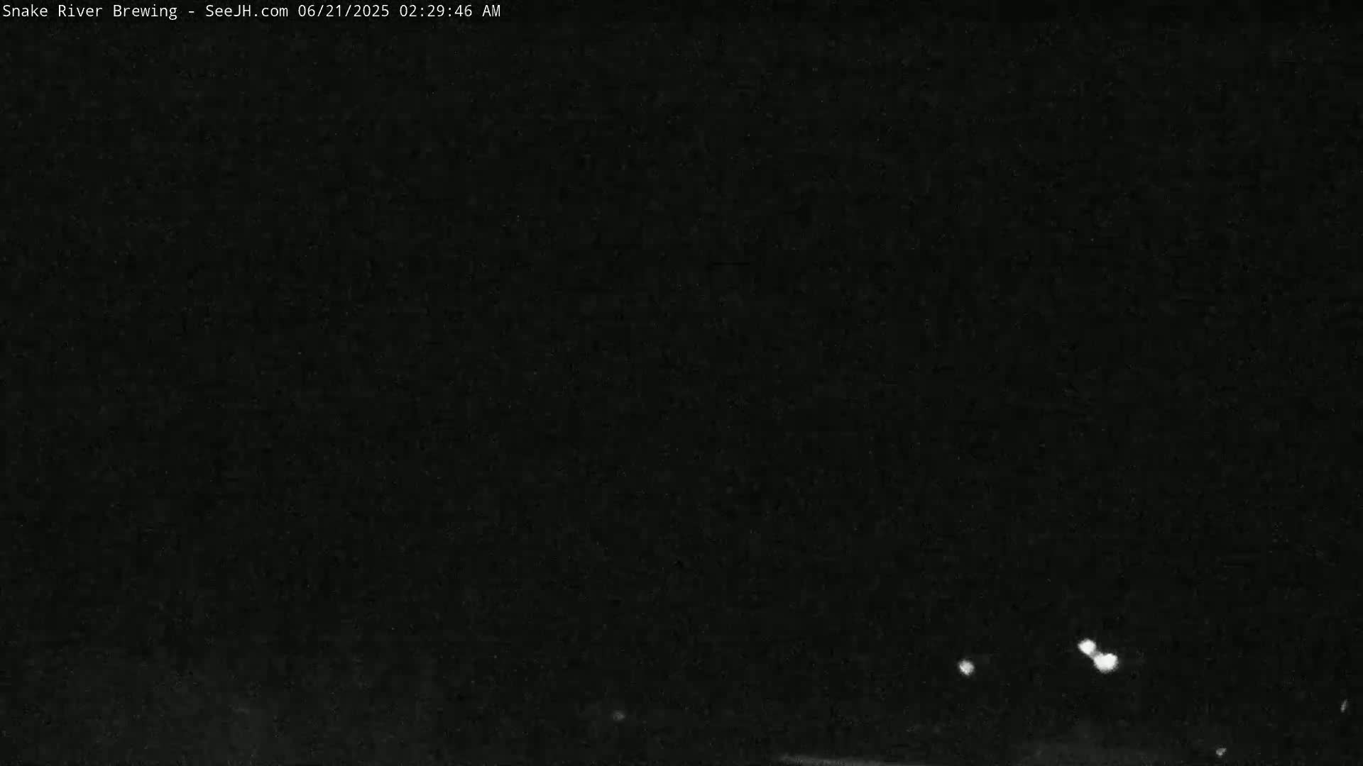 A nighttime, dark image shows a few faint white lights in the distance.