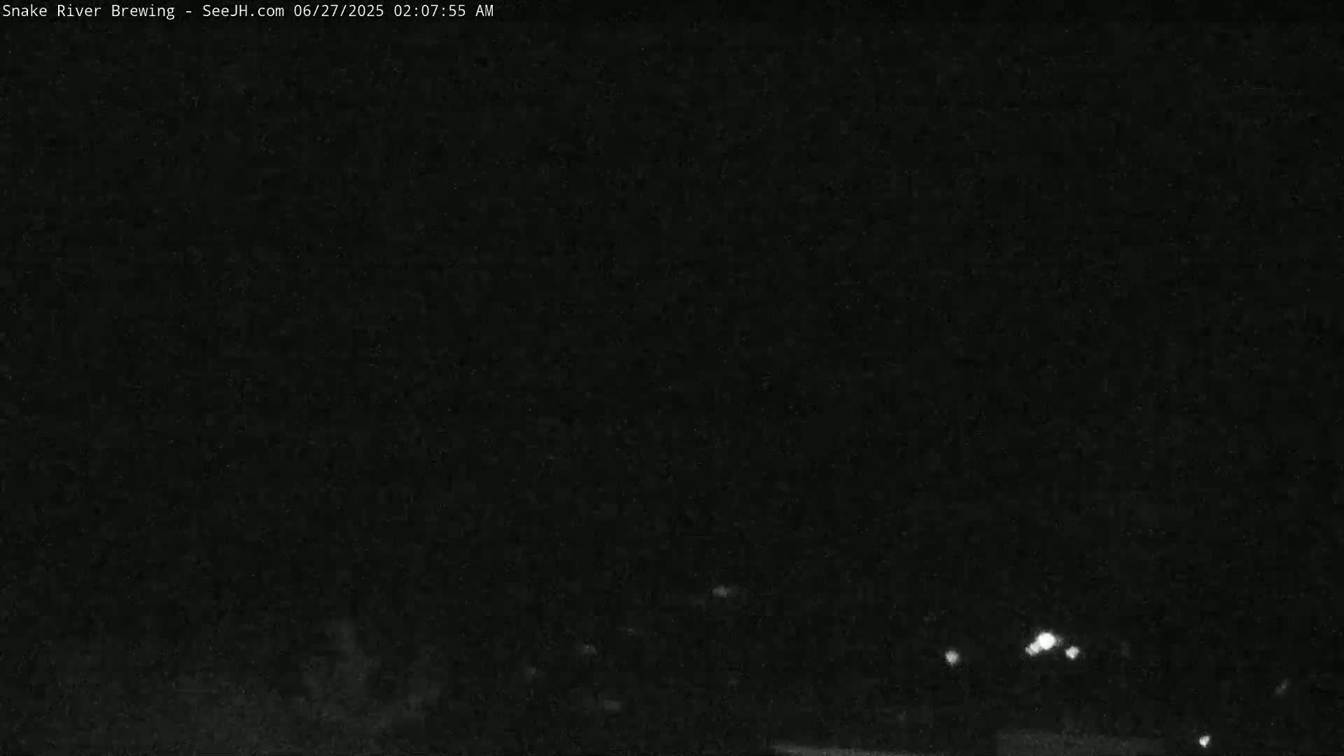 A nighttime, low-light outdoor scene shows a few distant, small lights in the dark.