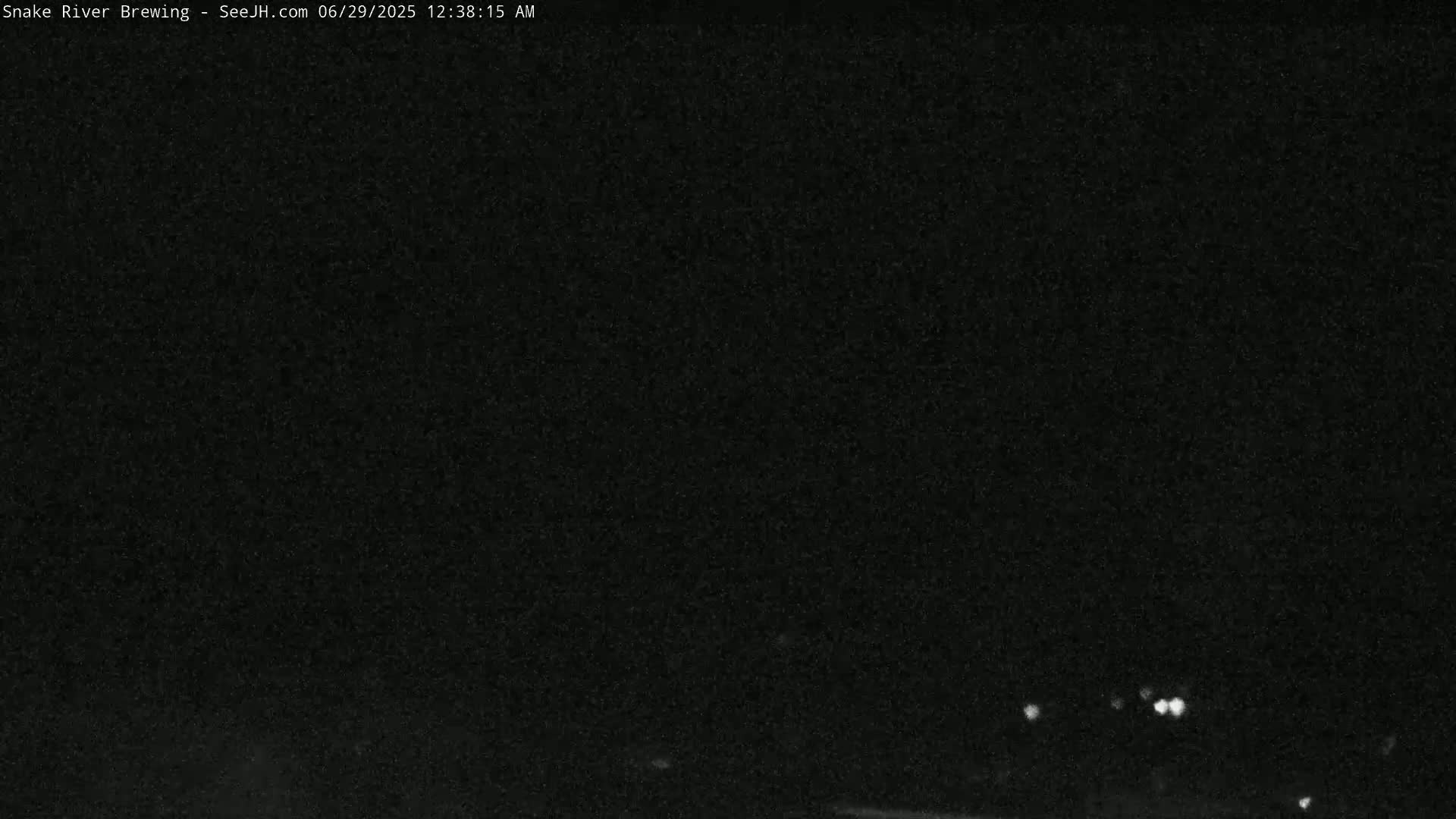 A dark, nighttime scene shows a few faint lights in the distance under a clear, dark sky.