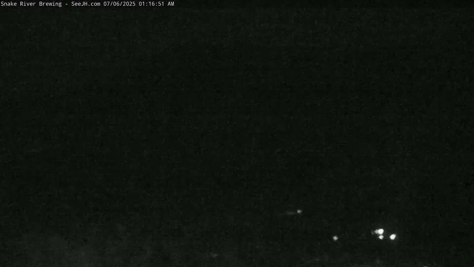 A nighttime image shows a dark sky with a few small, faint lights visible in the distance.