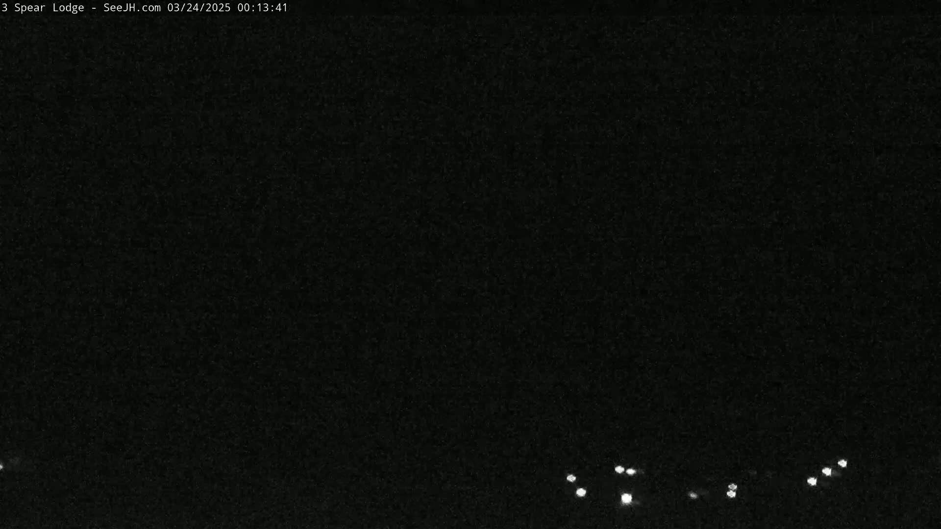 A nighttime, low-light image shows a dark, possibly overcast sky with a few distant lights visible at the bottom.
