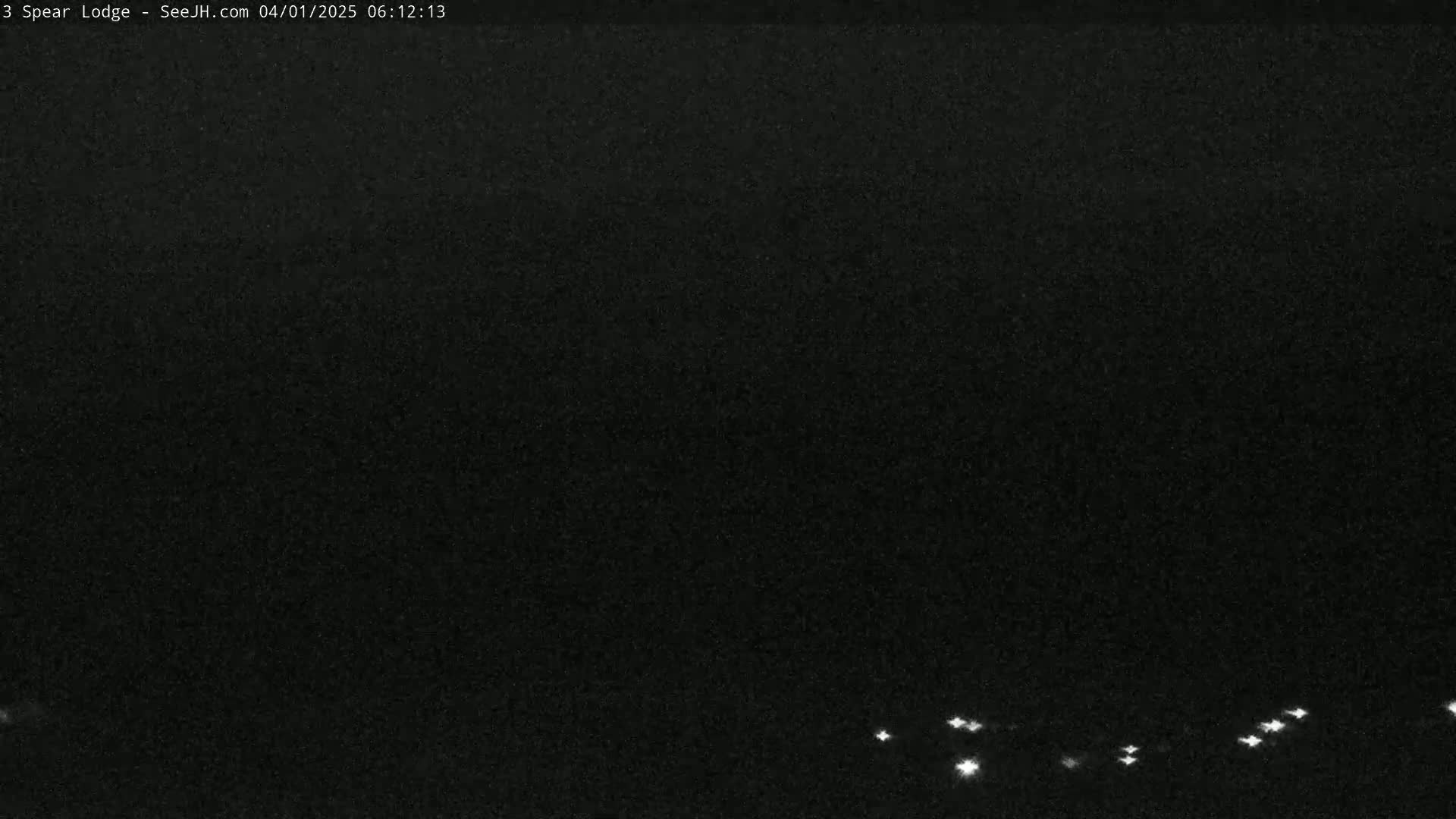 A dark, nighttime scene shows a few small, bright lights in the distance on a dark horizon.