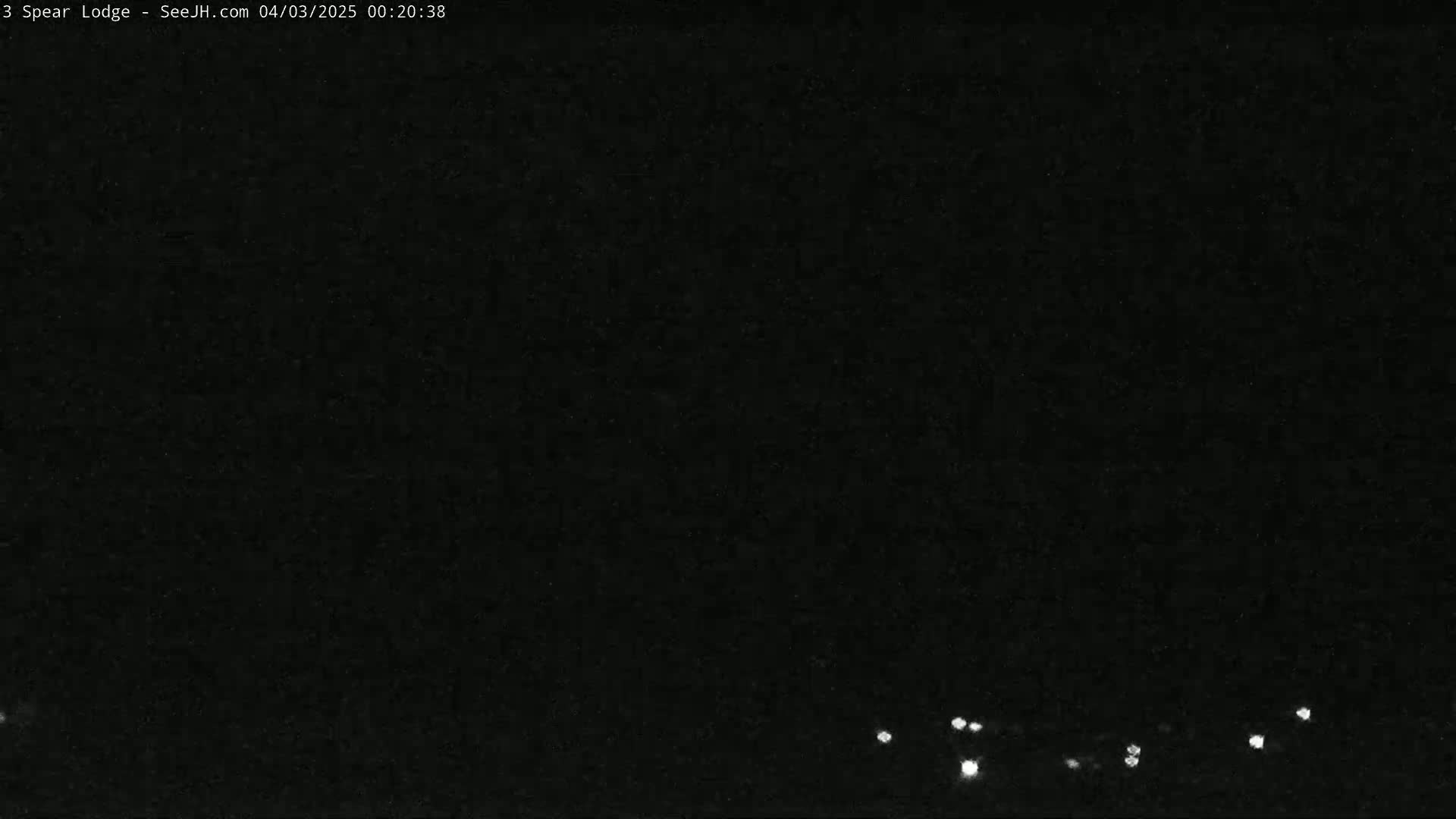 A dark, nighttime scene shows a few small, distant lights on the horizon.