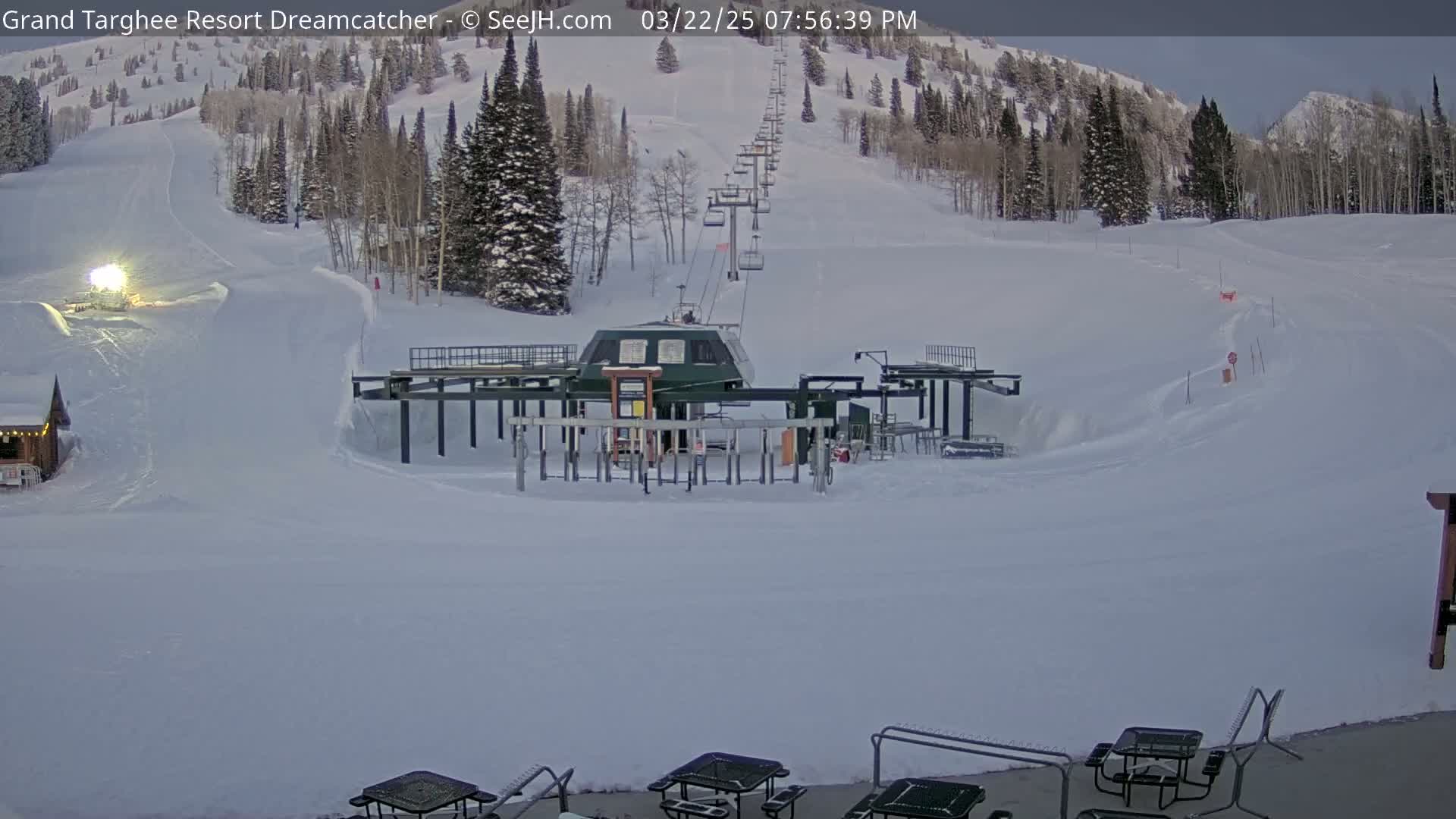 A chairlift and ski slope are covered in snow under a twilight sky.