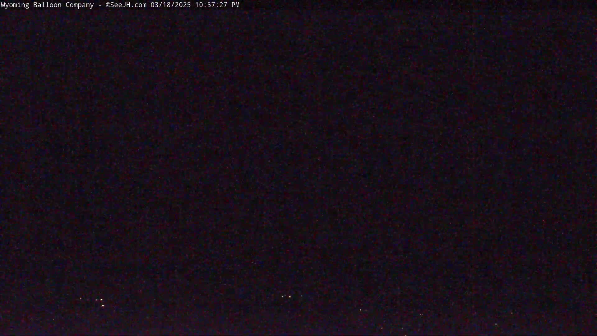 A dark nighttime sky with a few faint lights visible on the horizon.