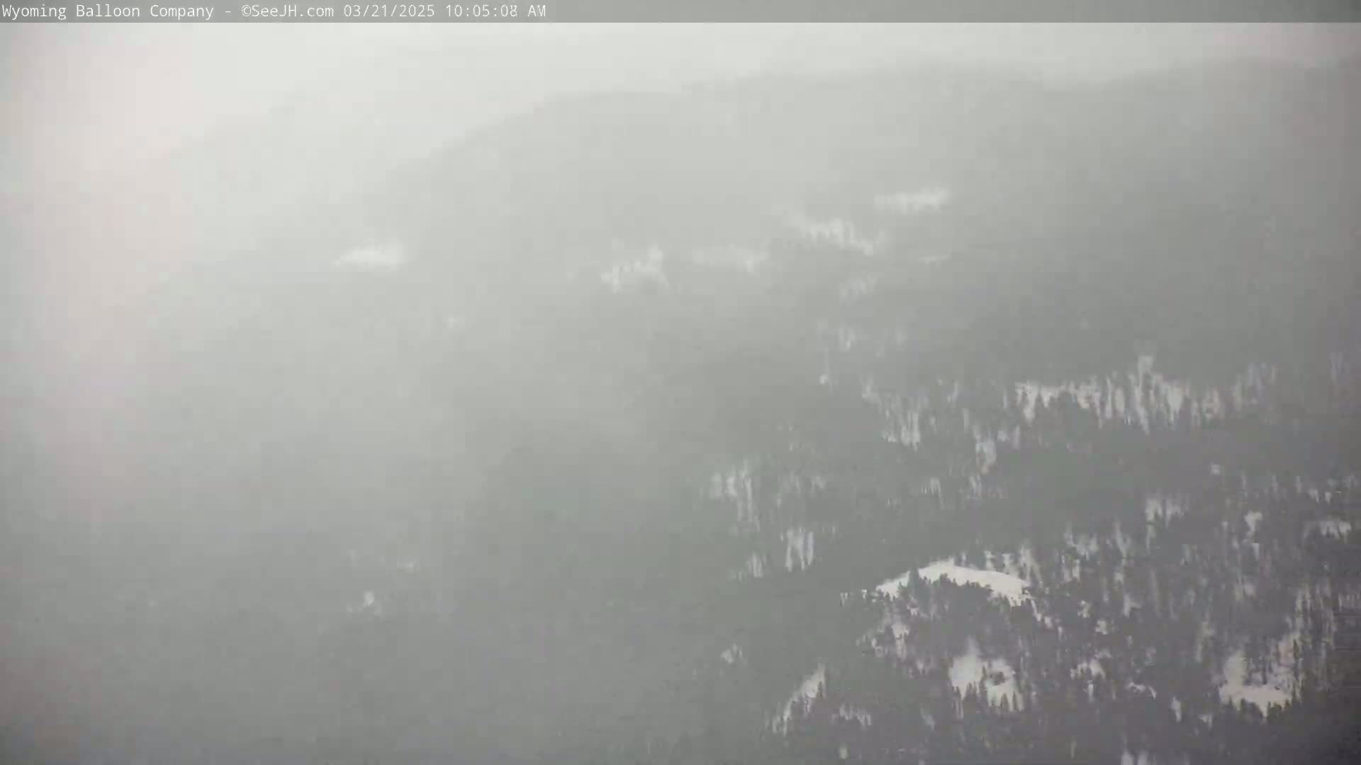 A hazy, snowy landscape of a dense forest is visible from a high vantage point.