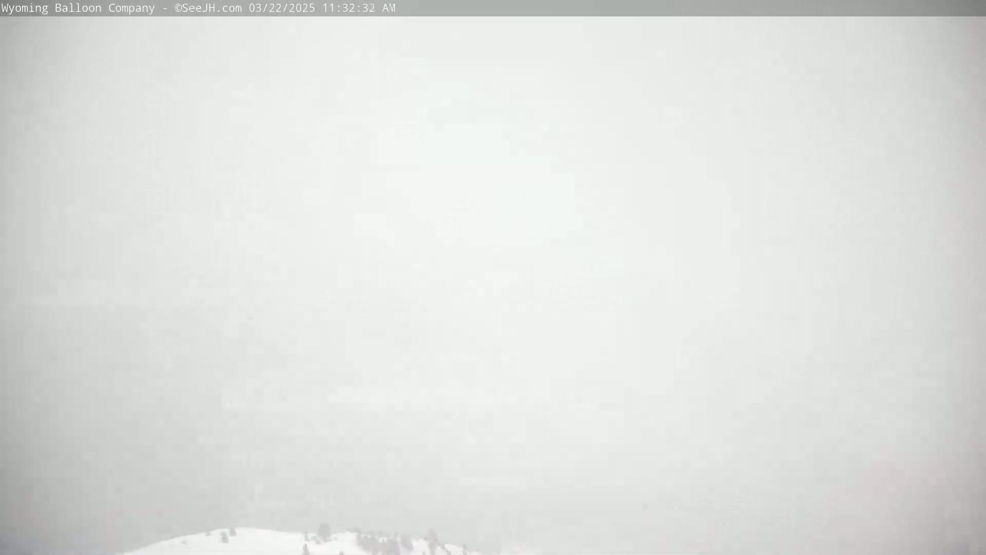 A mostly obscured view of a snowy ground with a few indistinct figures visible in a heavy fog or snow.