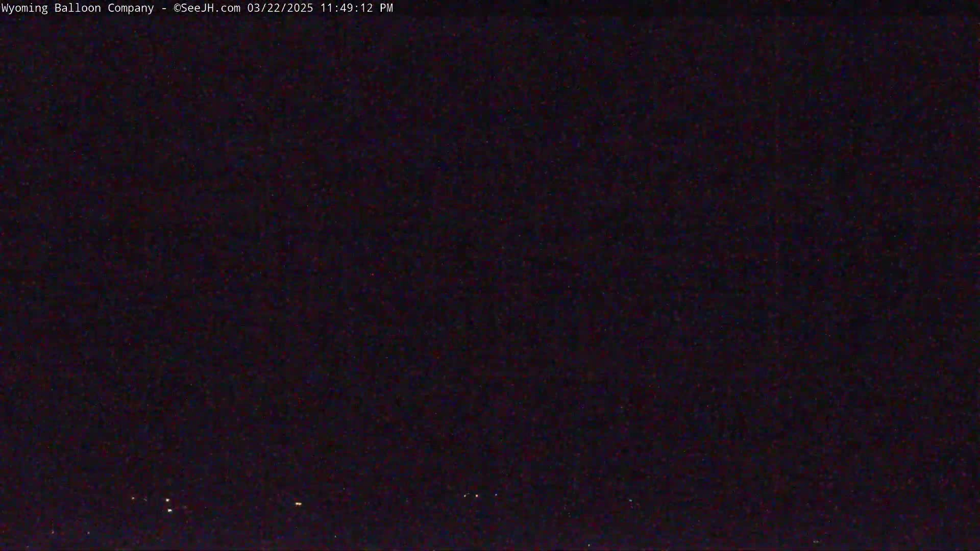 A dark, nighttime scene with a few faint lights visible on the horizon.